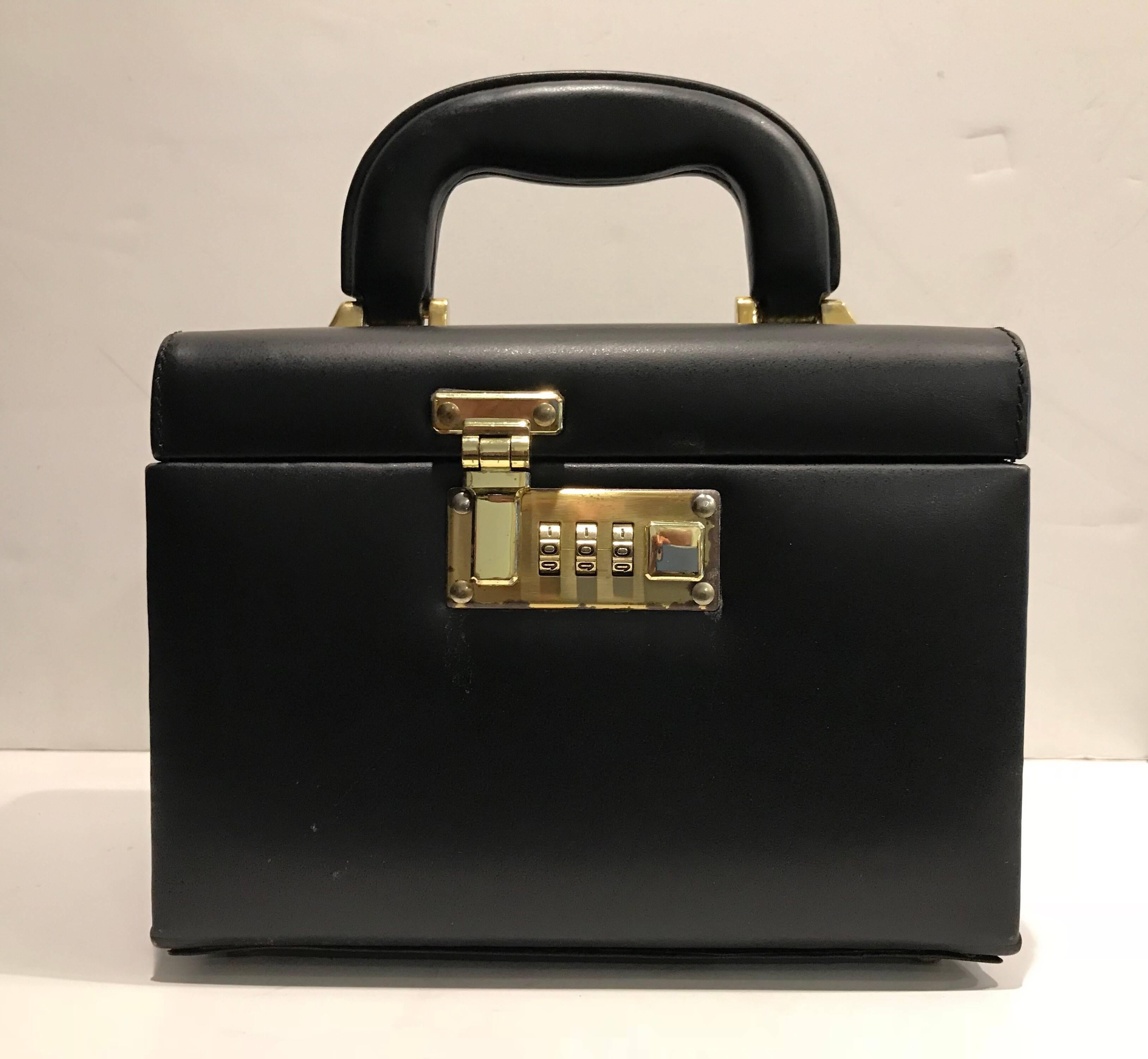 A lovely gift for yourself or a loved one!
1970s a very stylish Classic train case of black leather with brass combination lock, brass hardware,
and leather handle for ease of carrying.
Three faux suede lined removable drawers.
Mirror built into