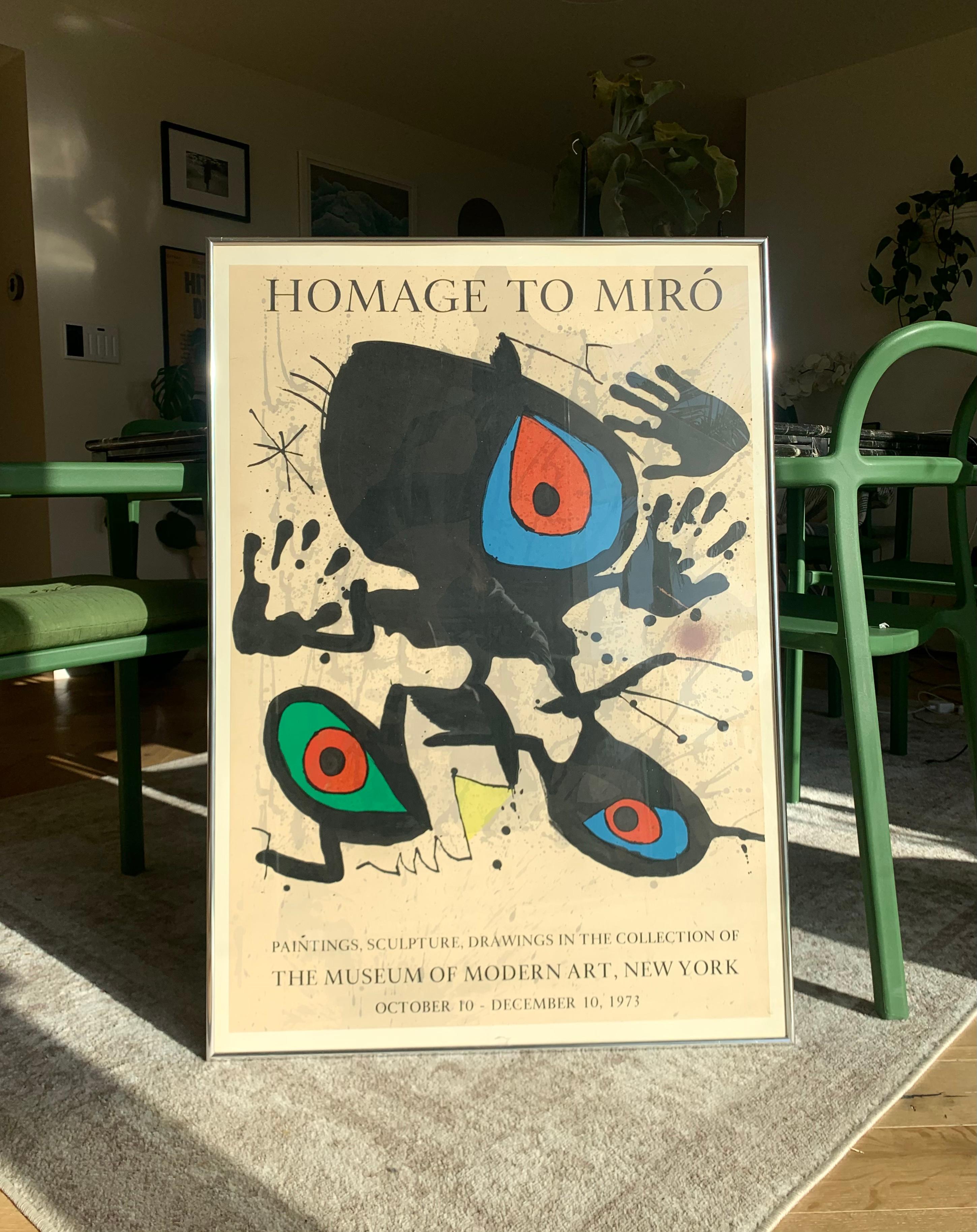 A vintage lithographic poster print of a Miró exhibition at MOMA. It reads

 “HOMAGE TO MIRÓ: Paintings, Sculpture, Drawings in the collection of the Museum of Modern Art, New York. October 10 - December 10, 1973”

Framed in aluminum and