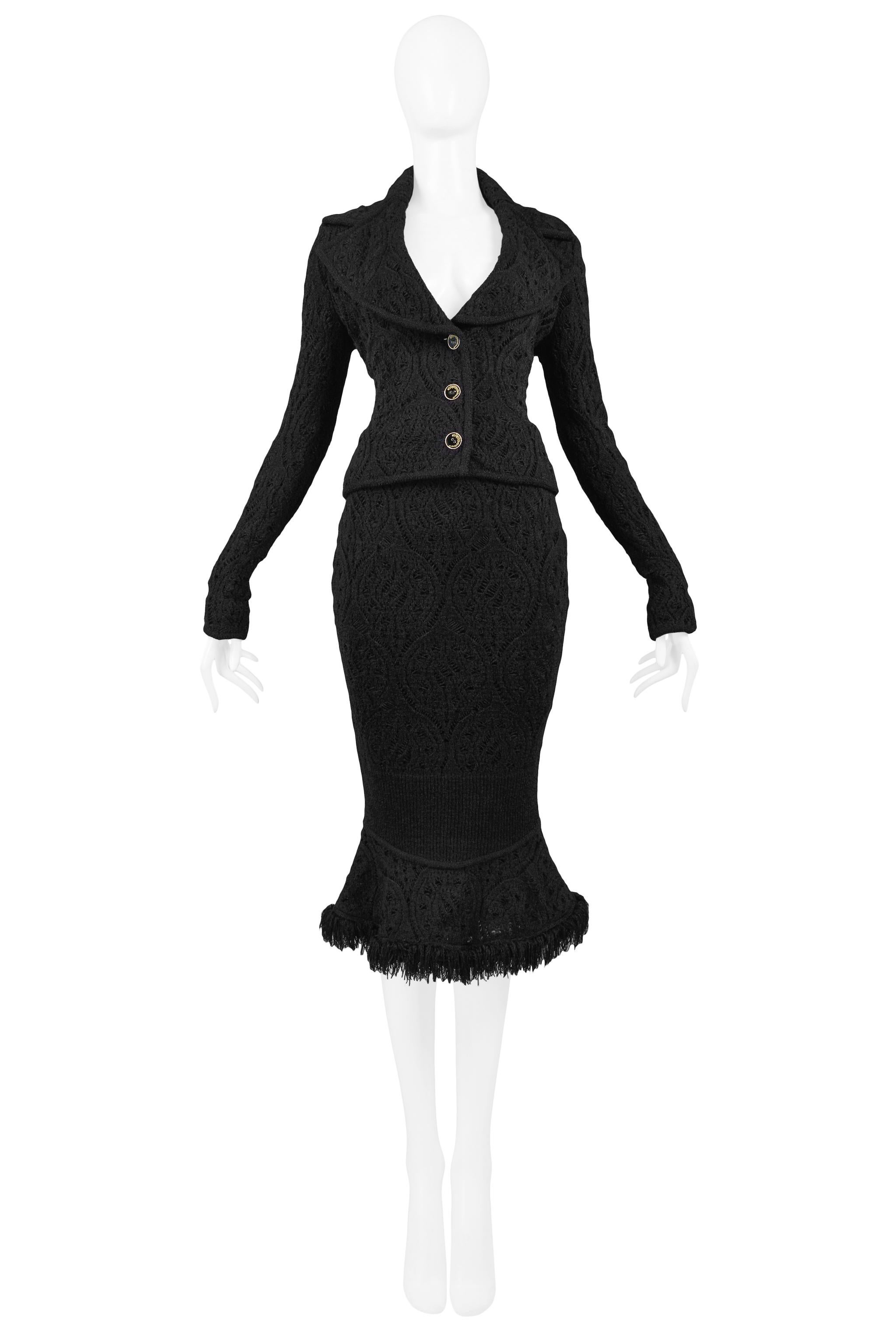 Vintage John Galliano black crochet skirt suit. The jacket features a deep neckline, large notched collar, and three-button closure at center front, and the skirt has a fitted silhouette with a flared fringe hem. Circa 1999.

Excellent Vintage