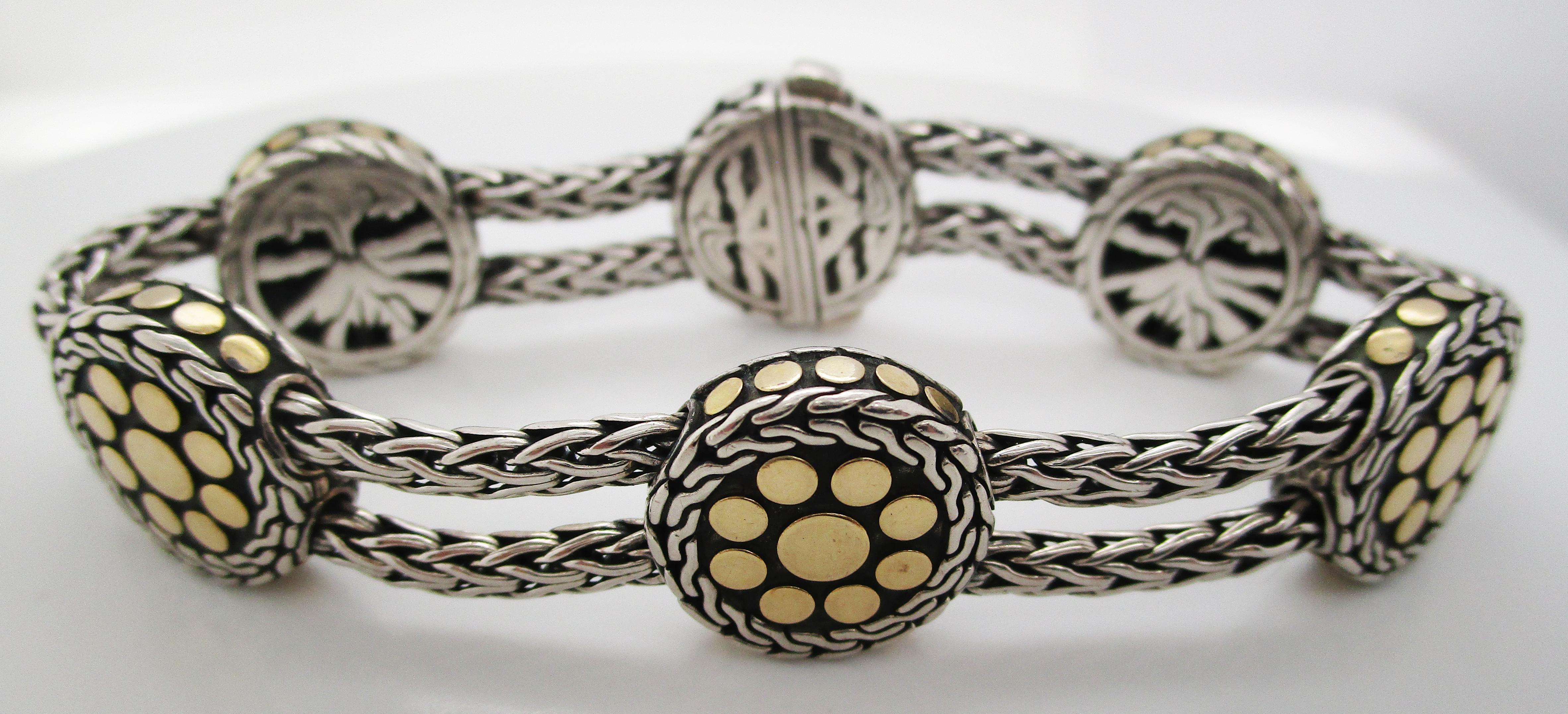This stunning vintage classic John Hardy bracelet is in sterling silver and 18k yellow gold. It features a unique design composed of silver discs with 18k yellow gold accents connected by two rows of sterling silver mesh chains. The design makes the