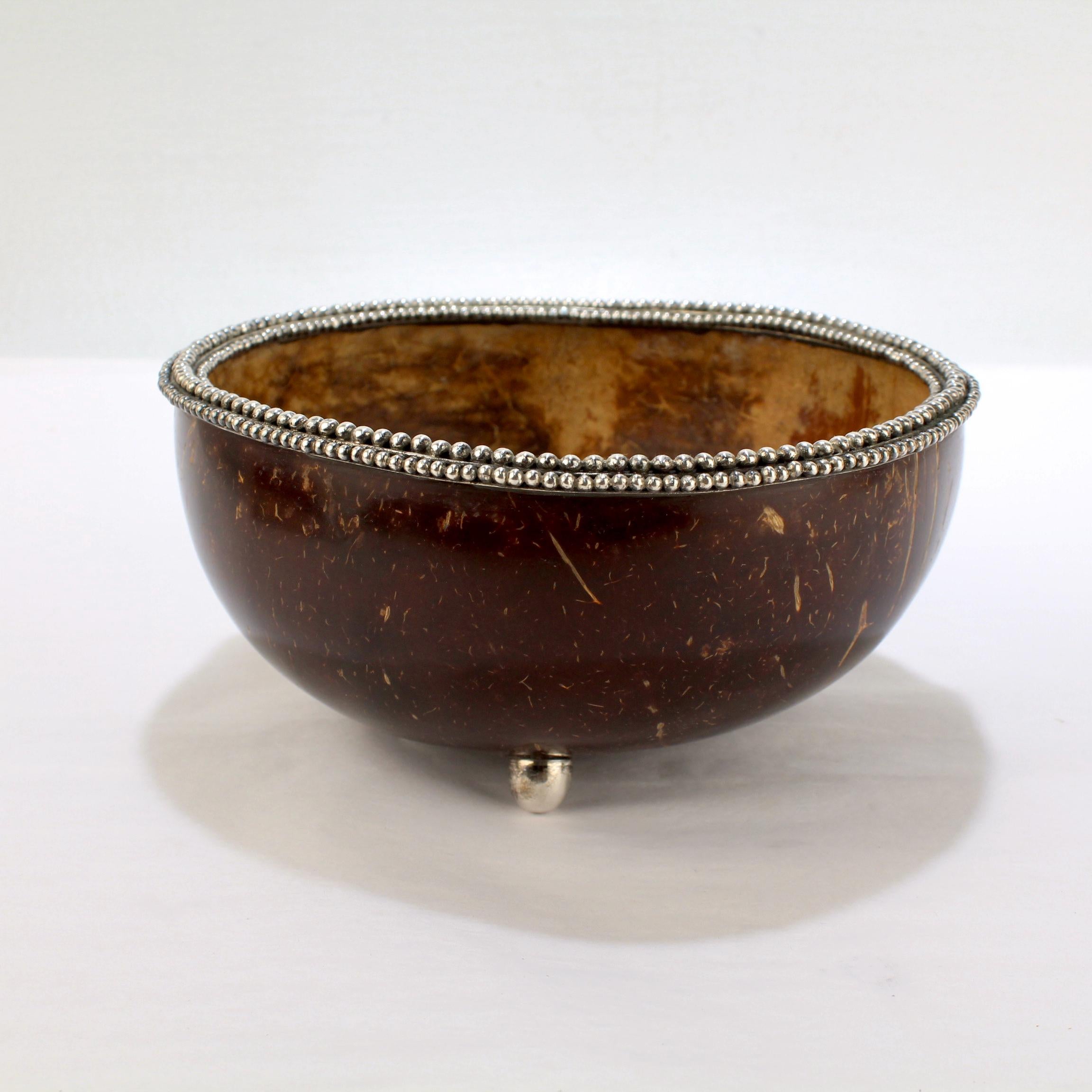 A wonderful bowl by John Hardy.

Constructed from half of a coconut shell.

Mounted with 3 sterling silver bullet shaped feet and a beaded sterling rim. 

(The bowl was likely produced in Bali).

Simply a great bowl!

Date:
20th