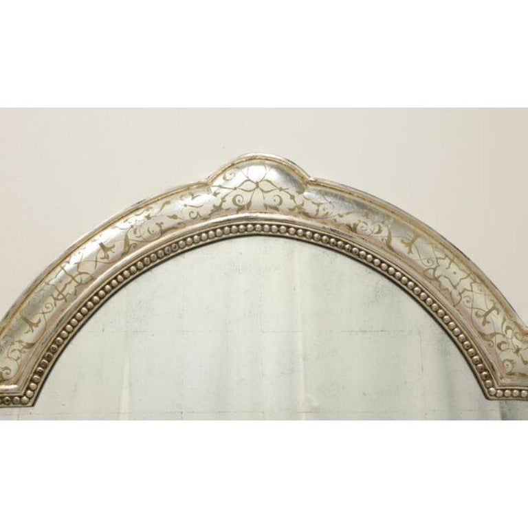 A Contemporary style, generously sized, wall mirror by John-Richard. Smokey block glaze to mirror glass in a decorative wood frame in an antiqued silver finish with a decorative arch design. Made in Asia, in the early 21st Century.

Measures: 47W