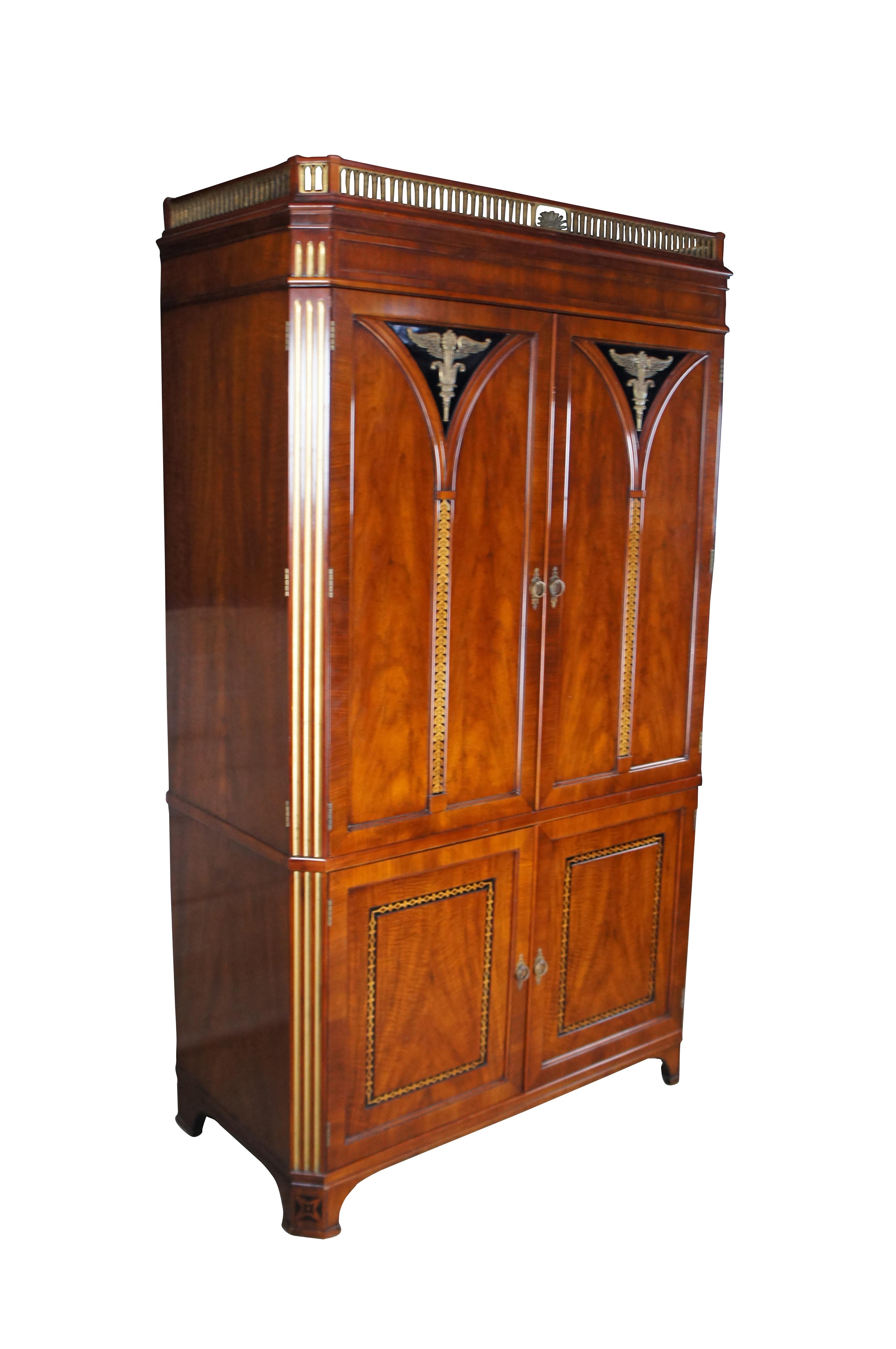 John Widdicomb French Empire / Deco inspired Armoire, circa 1970s. Made from cherry with paneled doors featuring ornate winged torchiere mounts in bronze over inlaid vine motif. Corners are chamfered and fluted in gold. The cabinet has an ornate