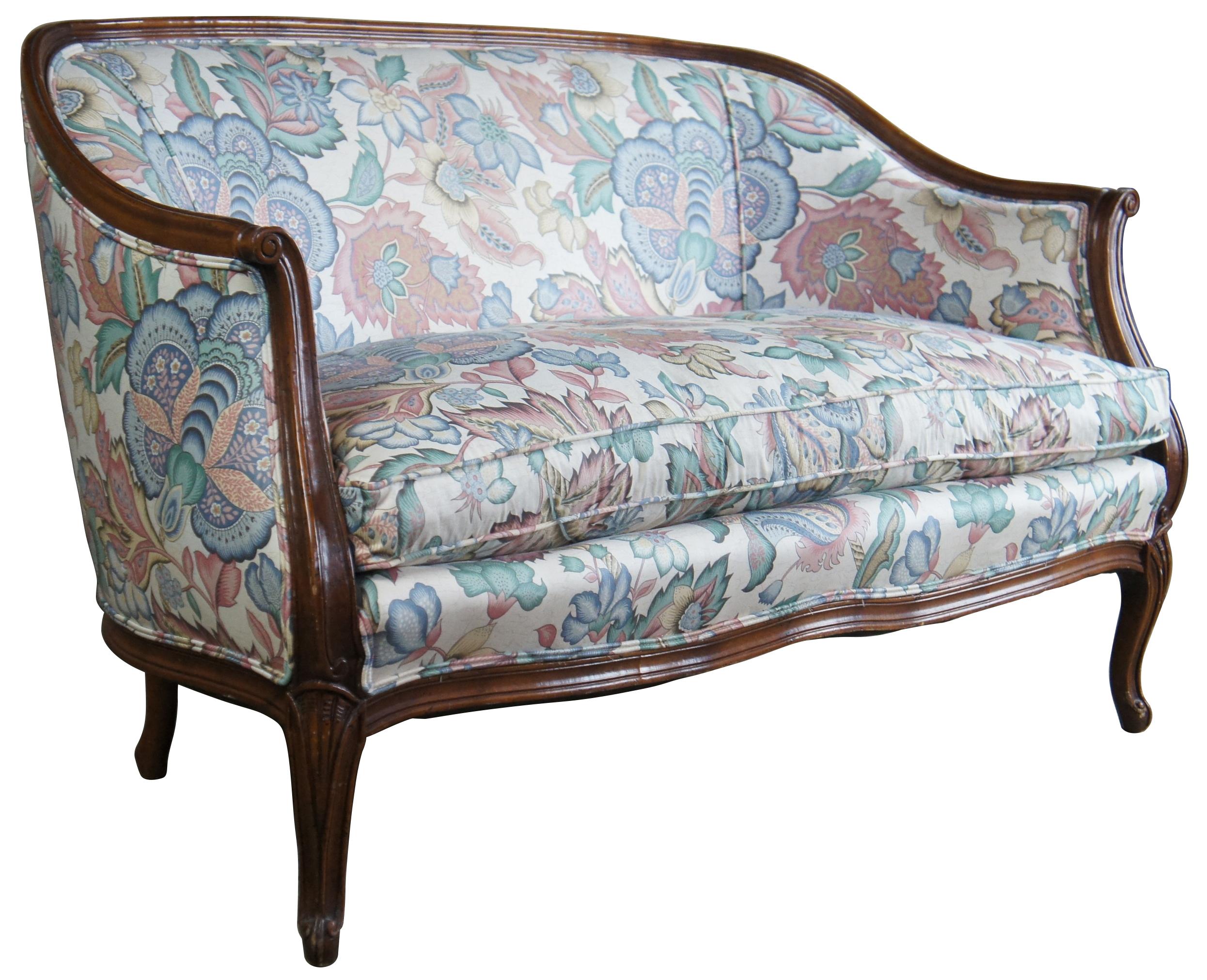 Circa 1980s John Widdicomb loveseat. Made from walnut with scrolled and flared arms over shell carved cabriole legs. Features a floral fabric with goose down and feather pillow by Betfara Corp. Draws inspiration from Louis XV and Provincial Styling.