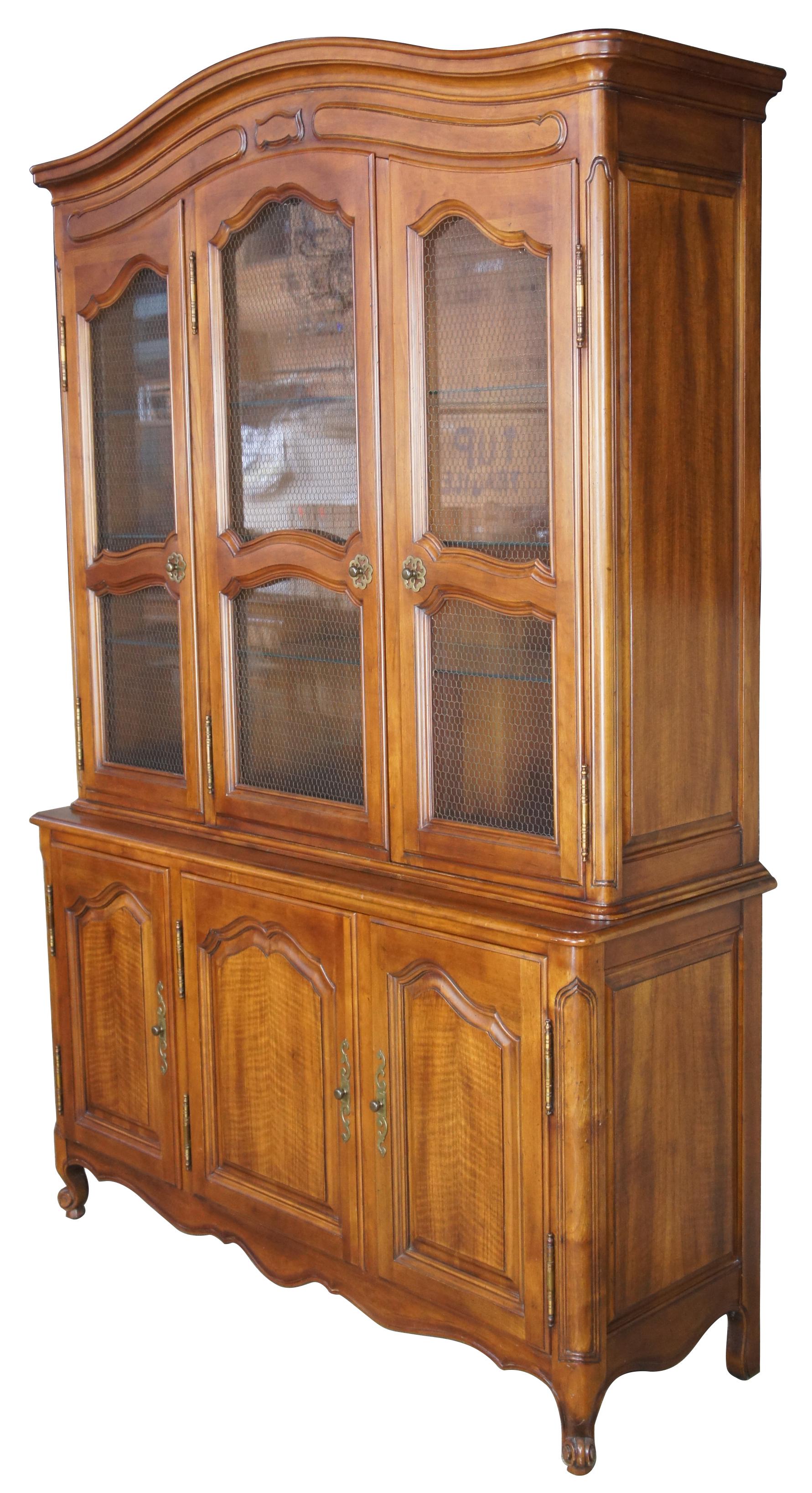 Circa 1980s John Widdicomb china cabinet. Made from walnut with serpentine shape, mesh / wire doors with three illuminated glass shelves, four silverware drawers and a cabinet. Draws inspiration from Louis XV and French Country / Provincial Styling.