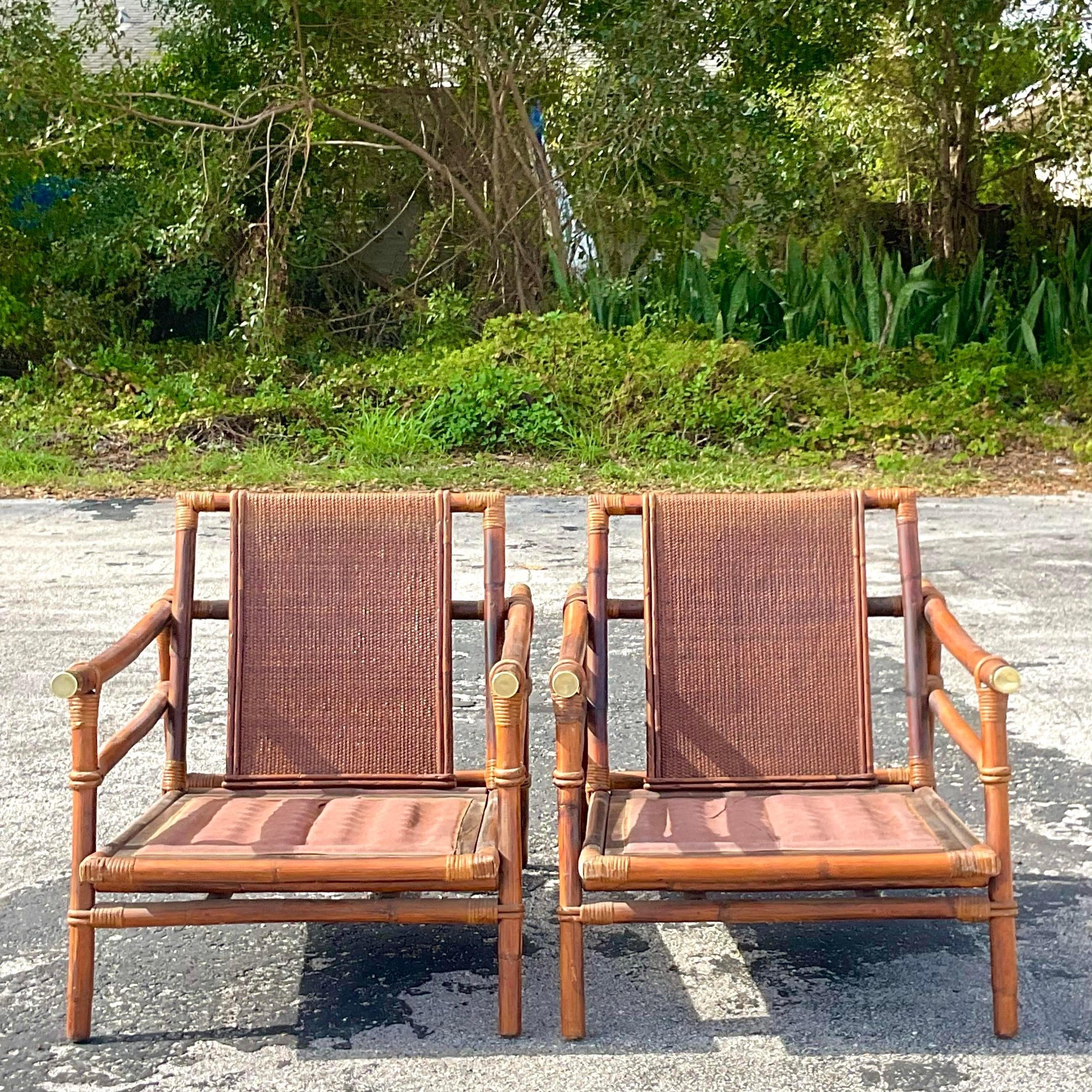 stunning pair of vintage Coastal rattan lounge chairs. Designed by John Wisner for the iconic Ficks Reed group. Beautiful woven rattan back panels and a sloped pagoda arm with brass end caps. Tagged on the seat frame. Acquired from a Palm Beach