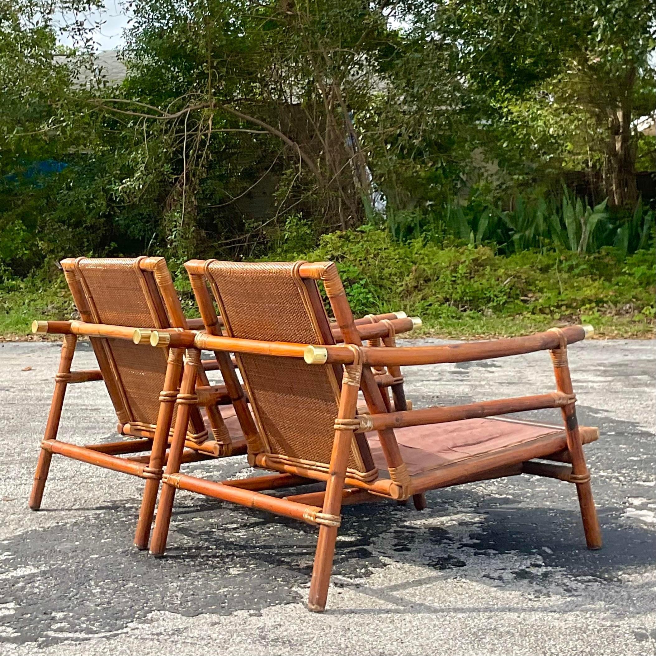 A stunning pair of vintage Coastal rattan lounge chairs. Designed by John Wisner for the iconic Ficks Reed group. Beautiful woven rattan back panels and a sloped pagoda arm with brass end caps. Tagged on the seat frame. Acquired from a Palm Beach