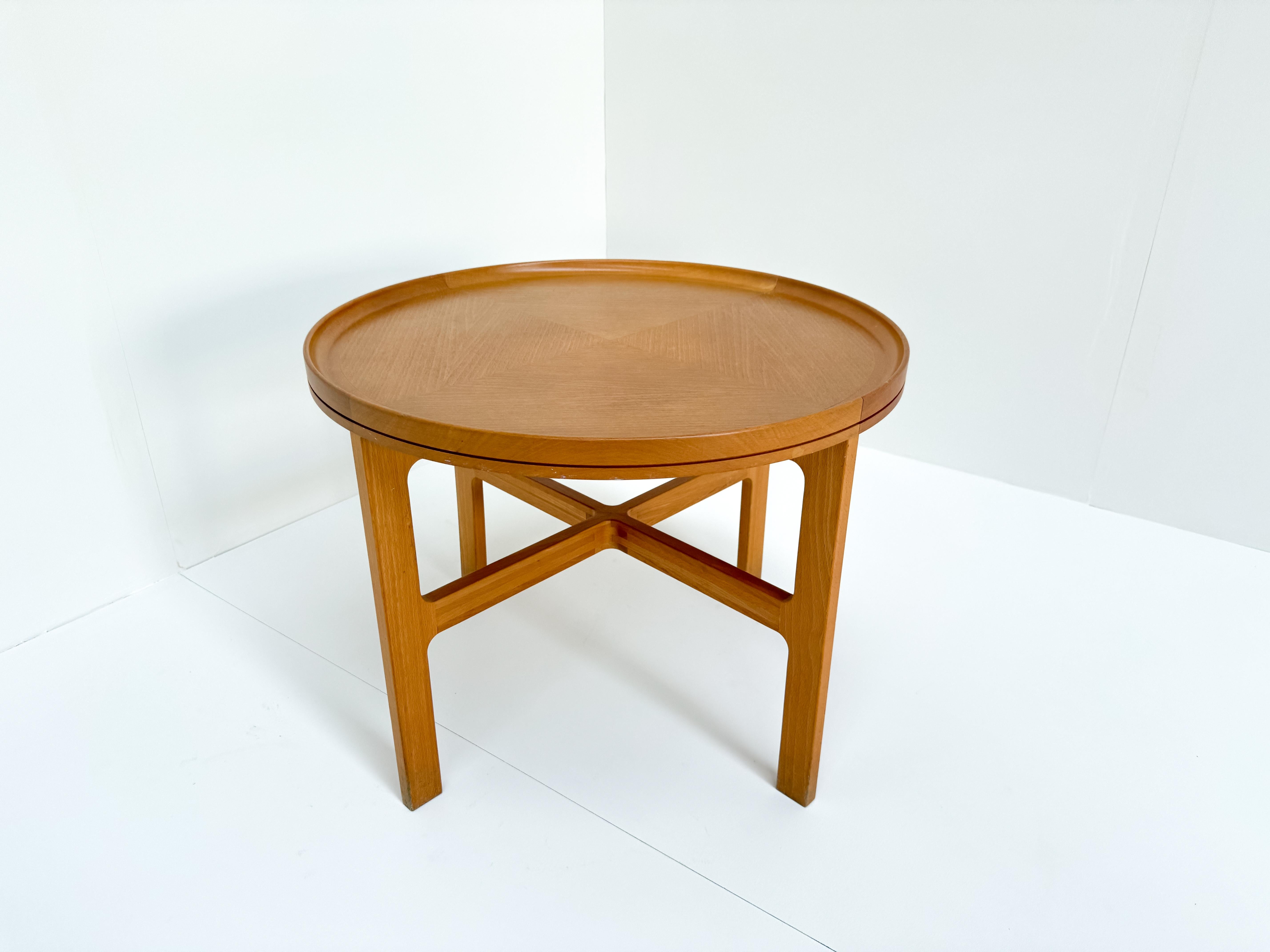 Mesa de centro vintage redonda de madera de haya con la pata cruzada, diseñada por Rud Thygesen y Johnny Sørensen, producida por Botium, Dinamarca, hacia 1975. La mesa tiene una altura de 54 cm y un diámetro de 70 cm. El diseño refleja un estilo
