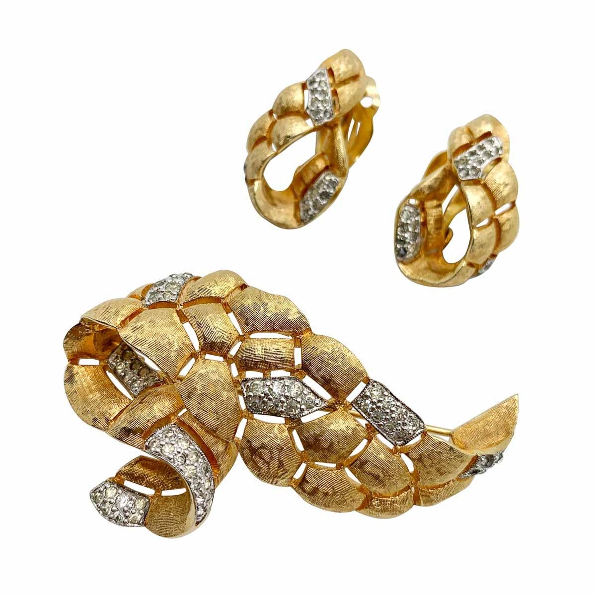 Eine alte Jomaz-Brosche und Ohrringe aus den 1960er Jahren. Sie zeichnet sich durch ein stilvolles Design im Swag-Stil, eine strukturierte goldene Verkleidung und kontrastierende, mit Pflastersteinen besetzte Kristallpaneele aus. Die Wurzeln des
