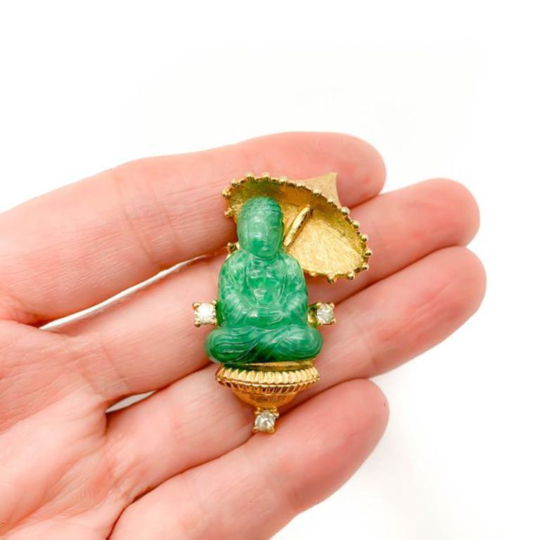 A delightful Vintage Jomaz Buddha Brooch. Featuring a lucky Buddha with parasol. Crafted from gold plated metal and set with a Peking glass Buddha and paste and accent crystals. 4cm. Very good vintage condition. Signed. A wonderful figural brooch