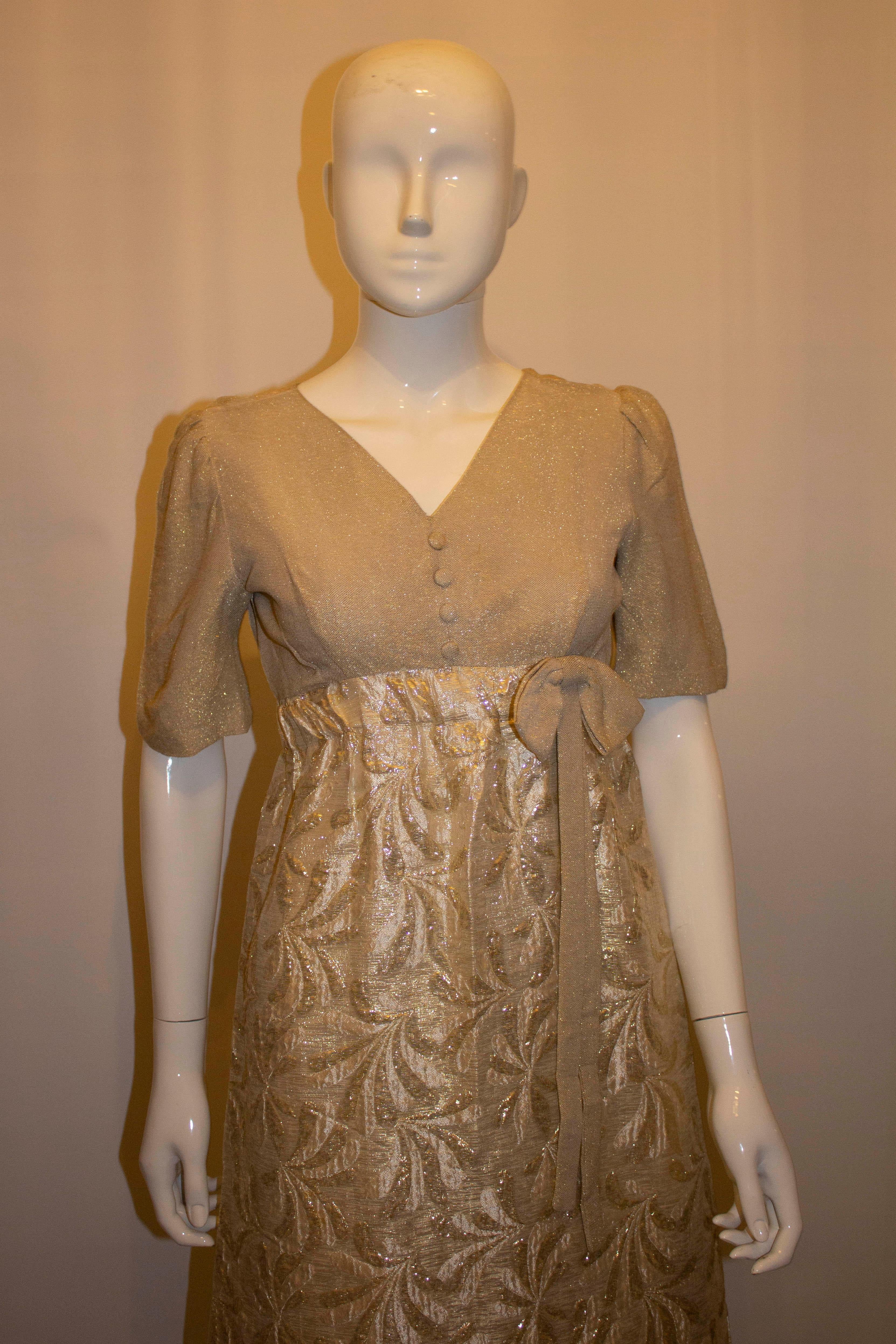 A pretty vintage evening gown by Joyce Palmer. The dress has a soft gold colour upper area and the skirt is a silver and gold mix. it has a v neckline and backline with a central back zip.
There is a 25'' slit on the right hand side . Measurements: