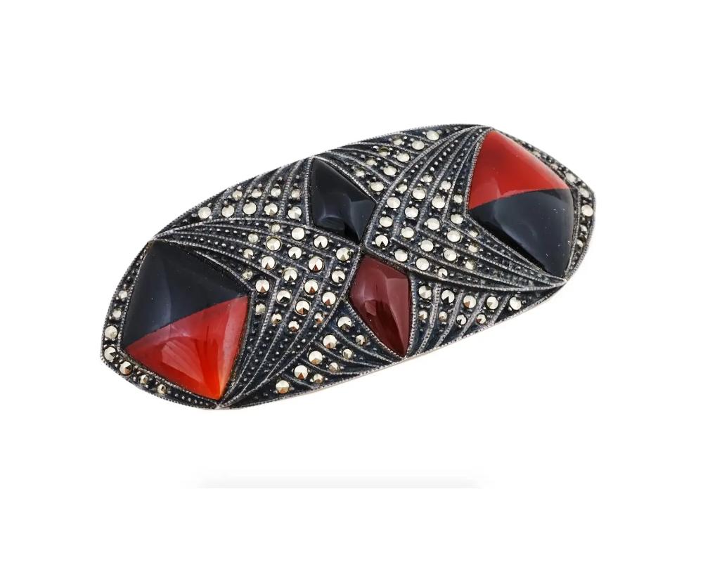 A vintage Sterling Silver pin brooch designed by Judith Jack, a high-end designer who specializes in marcasite jewelry, often with an Art Deco appearance. The brooch is made in a geometrical design, encrusted with onyx, Coral and Marcasite stones.