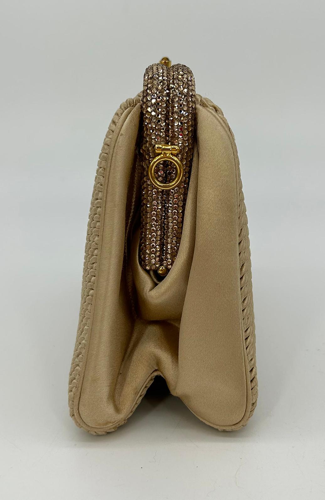 Vintage Judith Leiber Beige Pleated Silk Swarovski Crystal Top Clutch c1980s in good condition. Beige pleated silk exterior trimmed with gold hardware and swarovski crystal elements along top edge. Top tiger eye stone button closure opens to a