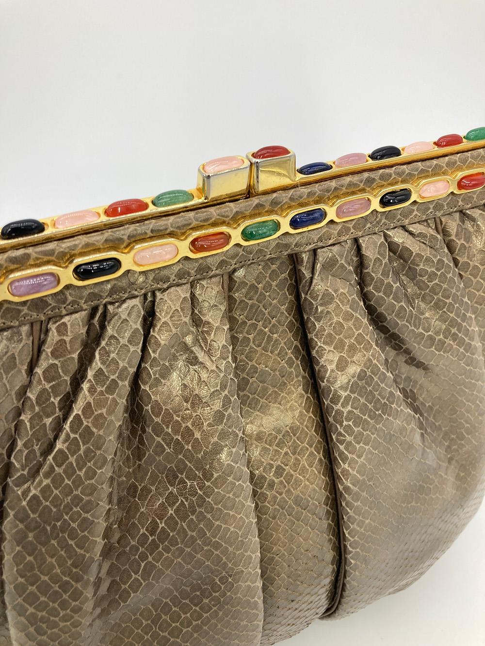 Vintage Judith Leiber Bronze Snakeskin Clutch in very good condition. Bronze pleated snakeskin exterior trimmed with gold hardware and multi color gemstones along top edges. Top kiss lock closure opens to a tan nylon interior with one zip and one
