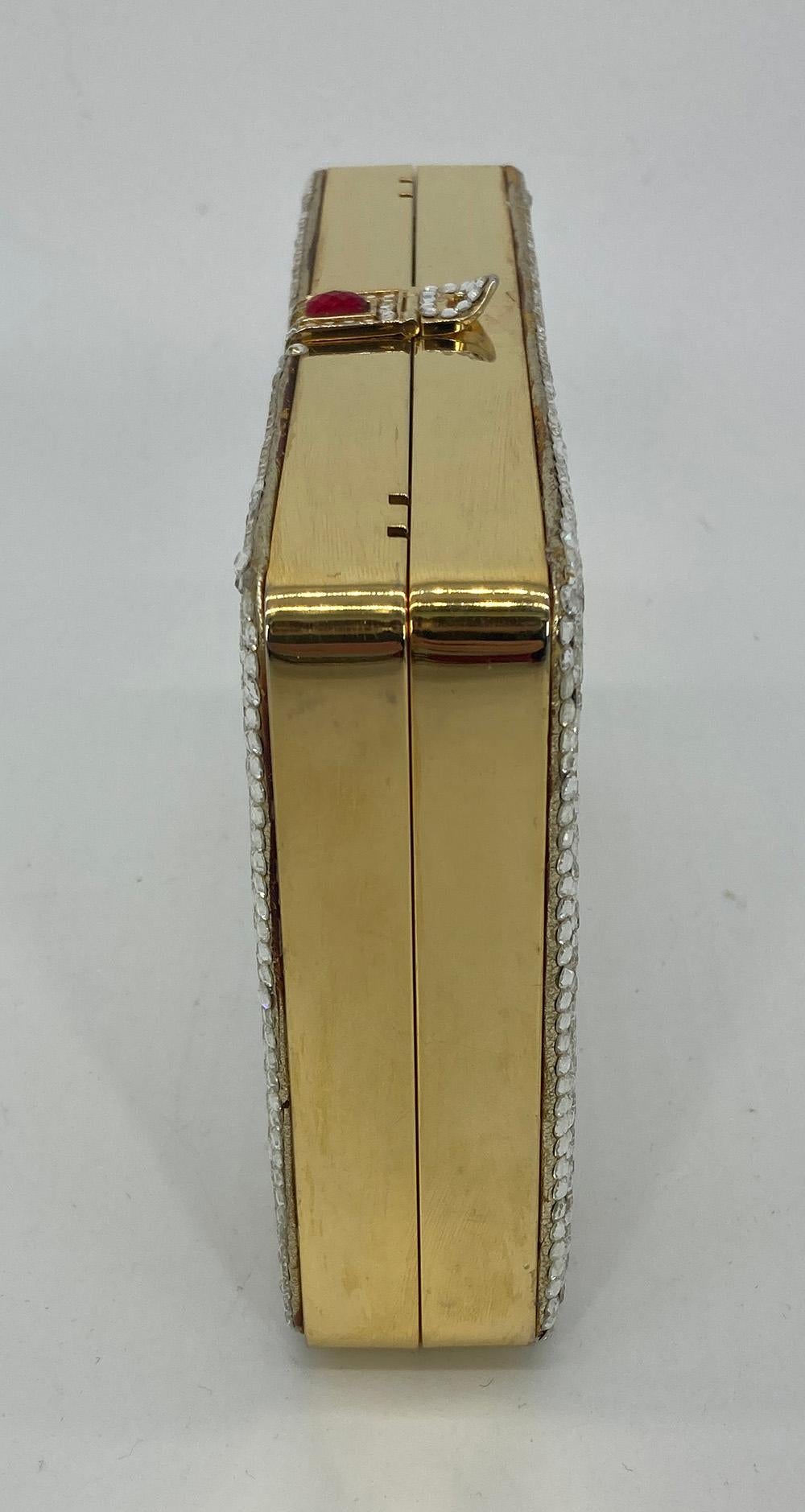 Judith Leiber Crystal Briefcase Minaudiere in good condition. Clear crystals over leather base trimmed with gold hardware. Top lift latch closure with red stone. gold leather interior with attached chain shoulder strap. Overall good condition with