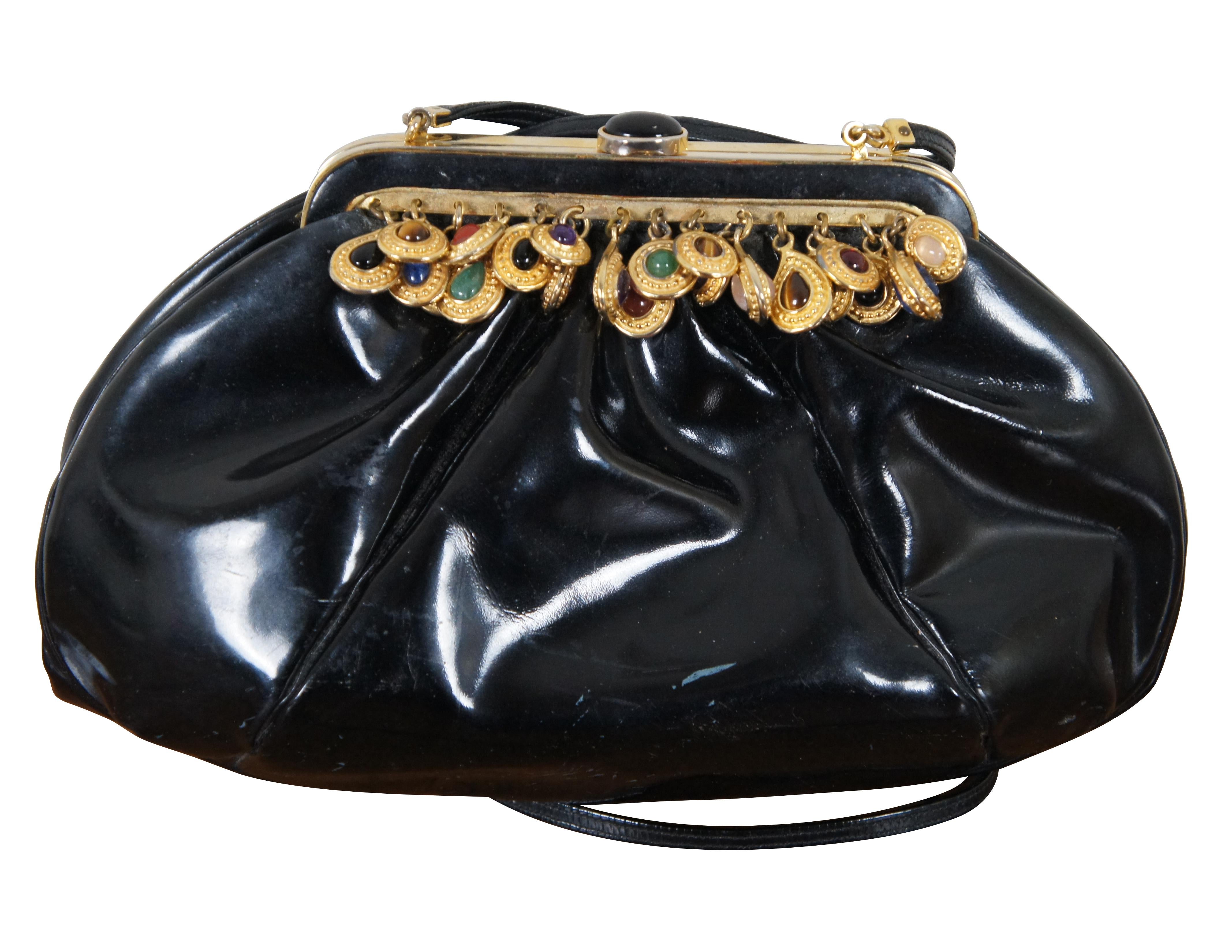 Vintage circa 1980s Judith Leiber black patent leather purse accented with multi-color jeweled charms along the clamshell clasp, featuring a thin shoulder strap, coin purse matching the red interior, and gold tone magnifying / double sided pocket