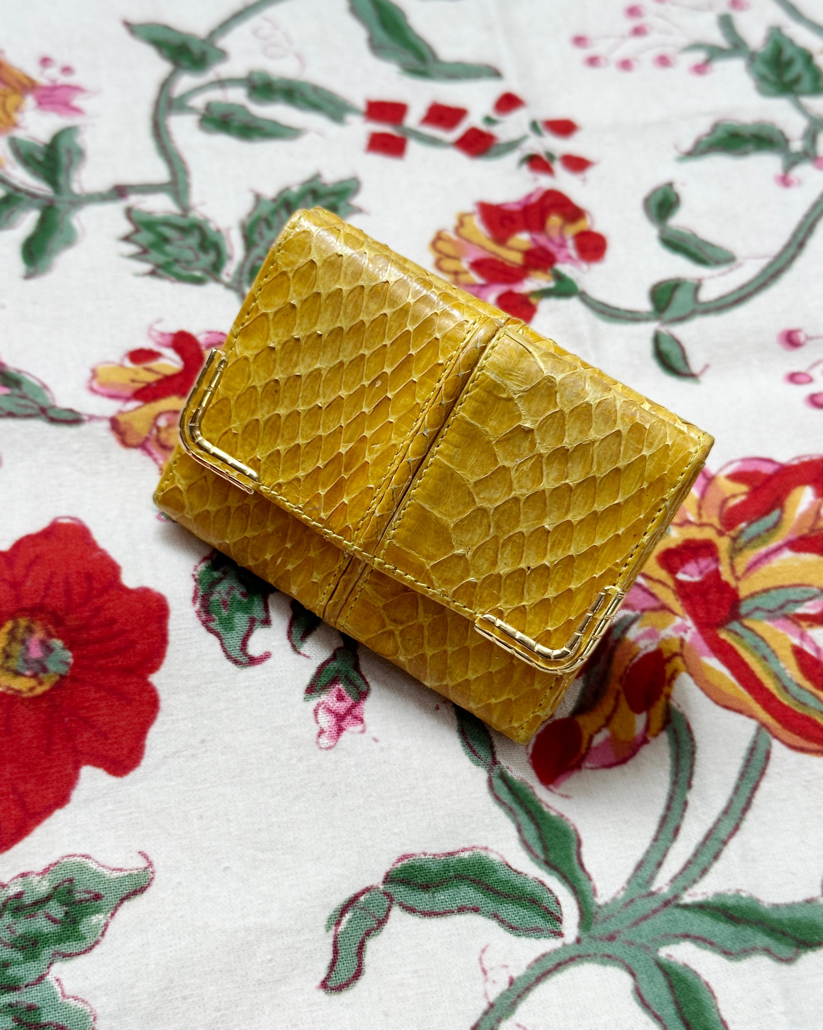 This vintage Judith Leiber yellow snakeskin wallet is simultaneously a collector's objets d’art, and a highly functional everyday necessity. Folded into a small rectangle, one side unfolds to hold bills, while the other has a snap that opens to a