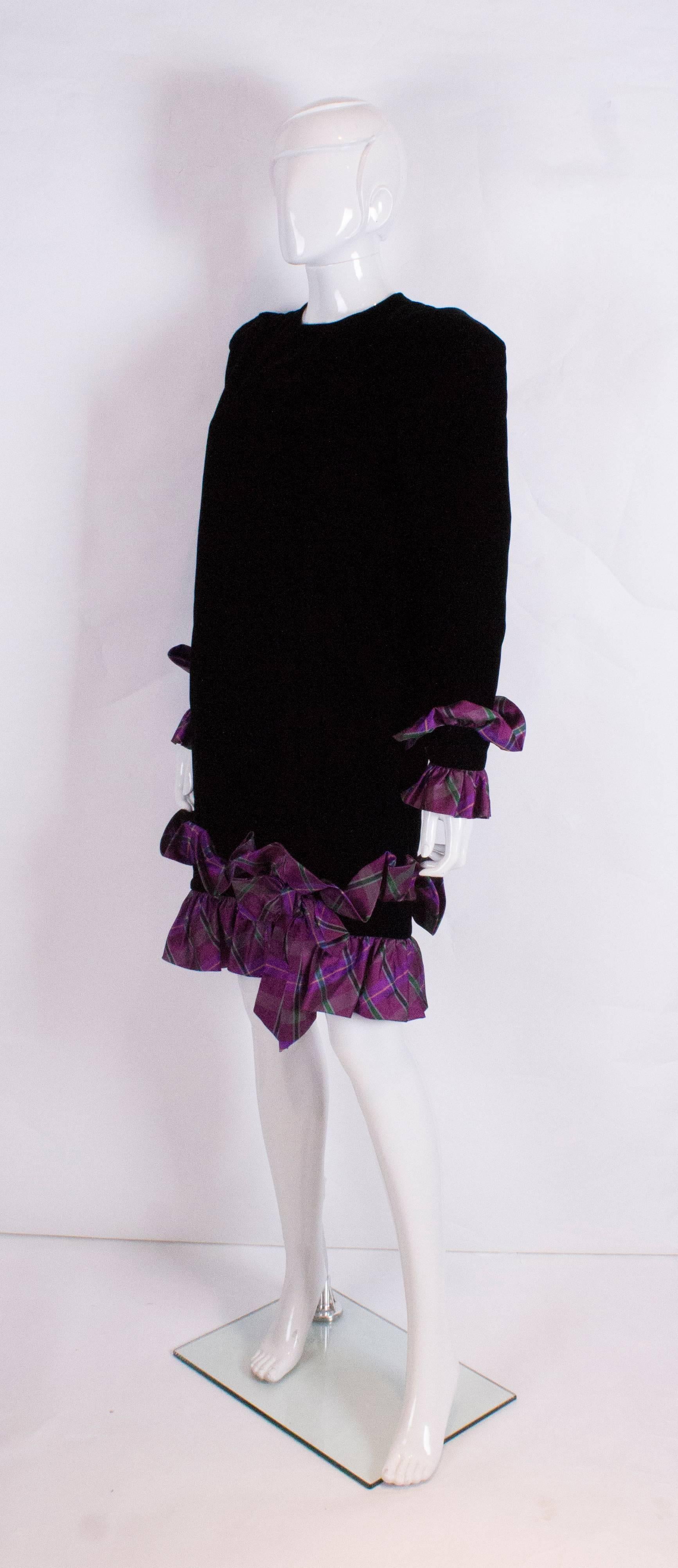 A chic vintage dress by Italian designer Juditte. The body of the dress is black velvet and the lilac tartan frills are on the hem and cuffs. The cuffs have two buttons and there is  a button opening at the back of the dress.