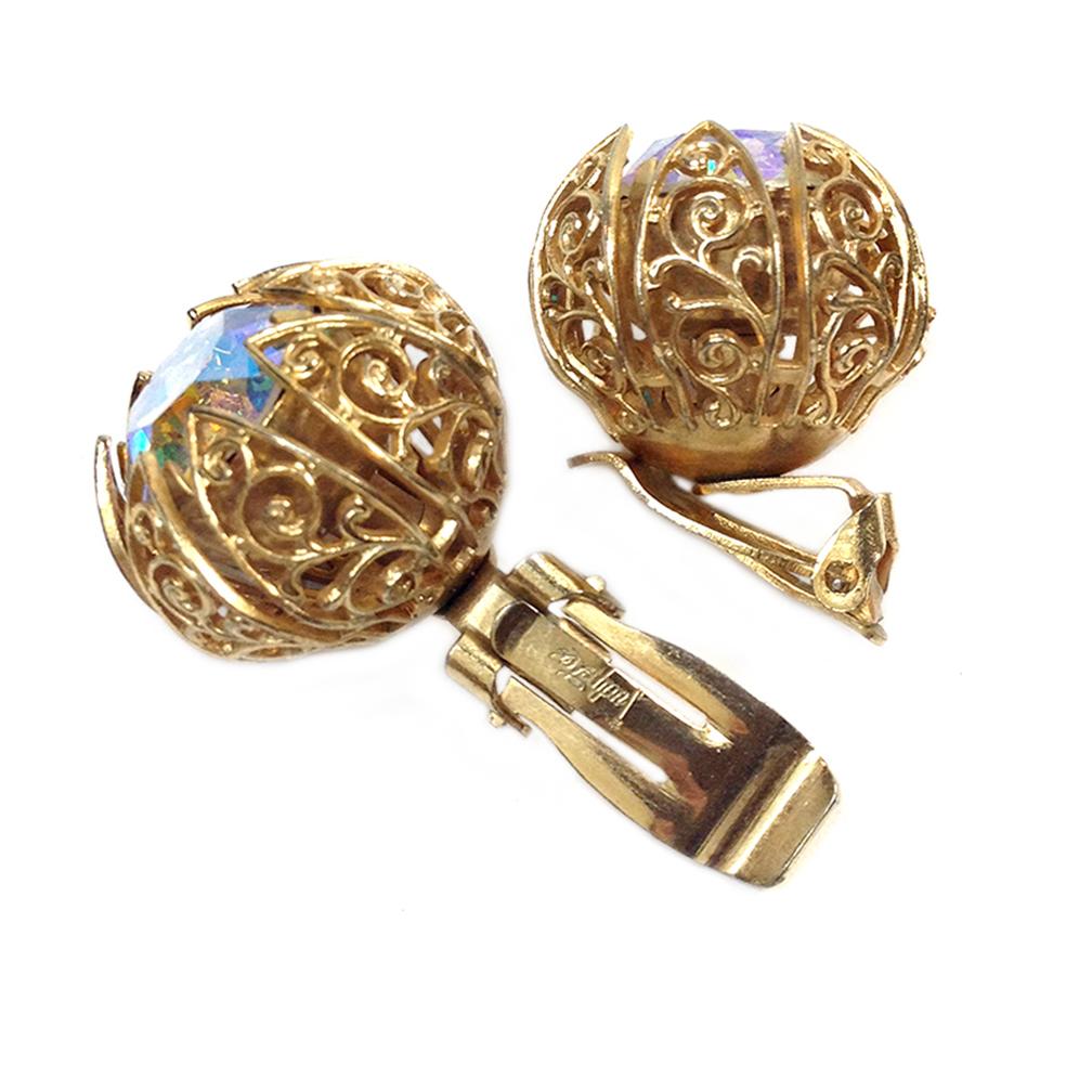 This is a pair of signed Judy-Lee rhinestone in gold-tone metal filigree petals clip back earrings. Two top quality 15 mm aurora borealis treated faceted round rhinestones blink like a sporty car's headlights in the night.

Popular in the 1950’s