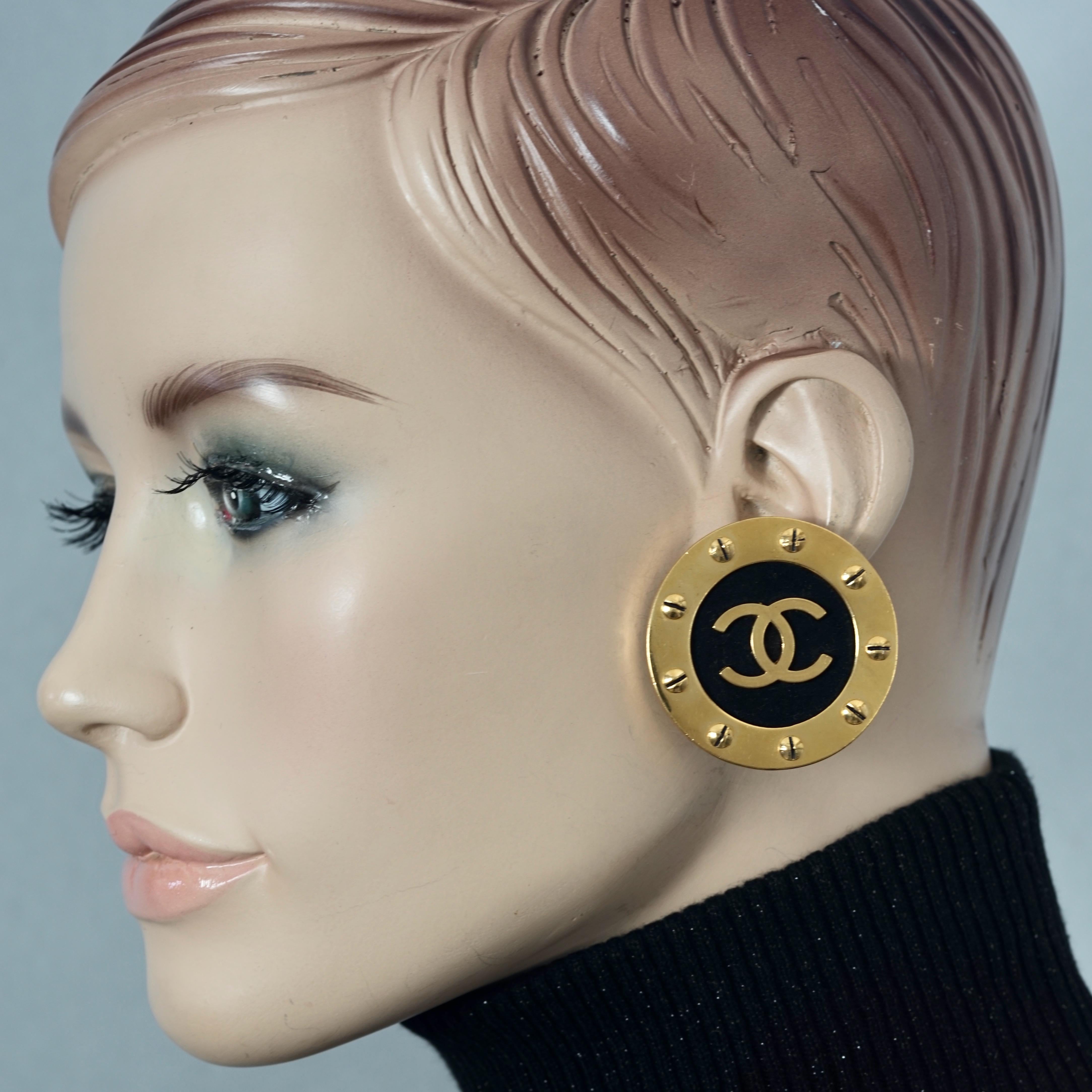 Vintage Jumbo CHANEL CC Logo Screw Disc Earrings

Measurements:
Height: 1.65 inches (4.2 cm)
Width: 1.65 inches (4.2 cm)
Weight per Earring: 25 grams

Features:
- 100% Authentic CHANEL.
- Jumbo Chanel disc earrings with screw embellishments, black