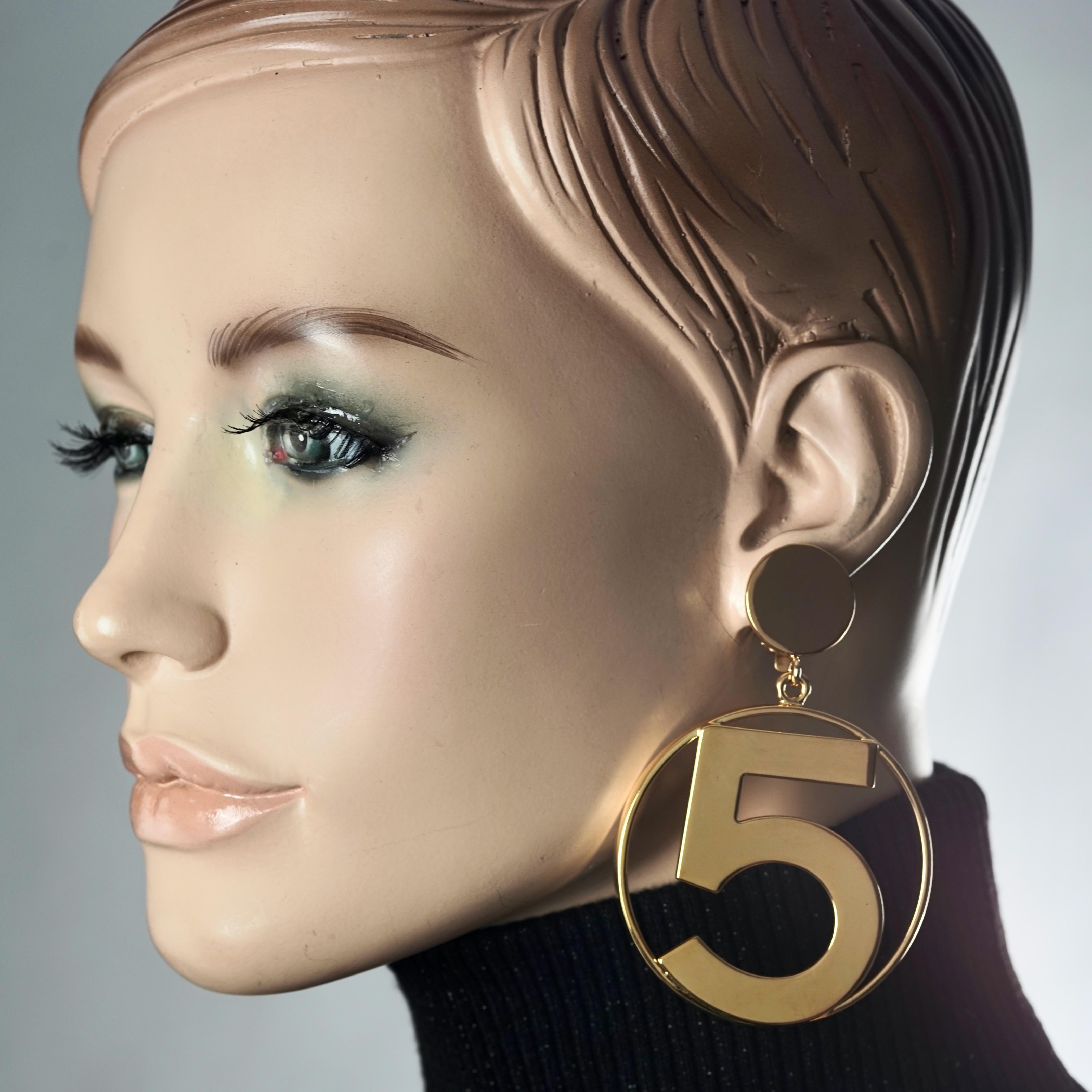 Vintage Jumbo CHANEL Iconic No 5 Hoop Earrings

Measurements:
Height: 3.35 inches (8.5 cm)
Width: 2.20 inches (5.6 cm)
Weight per Earring: 34 grams

Features:
- 100% Authentic CHANEL.
- Massive hoop earrings with No. 5 at the centre.
- Gold tone