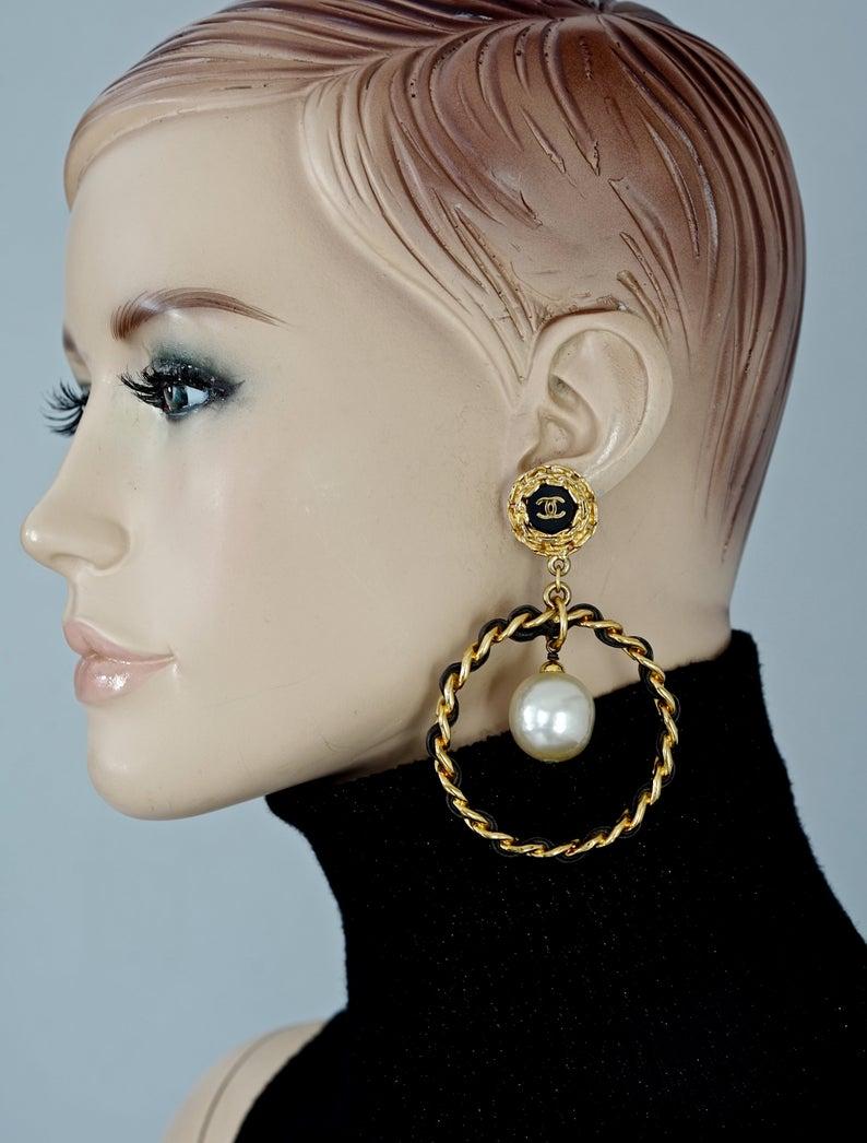 Vintage Jumbo CHANEL Logo Pearl Leather Chain Hoop Earrings

Measurements:
Height: 3.42 inches (8.7 cm)
Width: 2.28 inches (5.8 cm)
Weight per Earring: 38 grams

Similar earrings seen on Rihanna.

Features:
- 100% Authentic CHANEL.
- Iconic leather