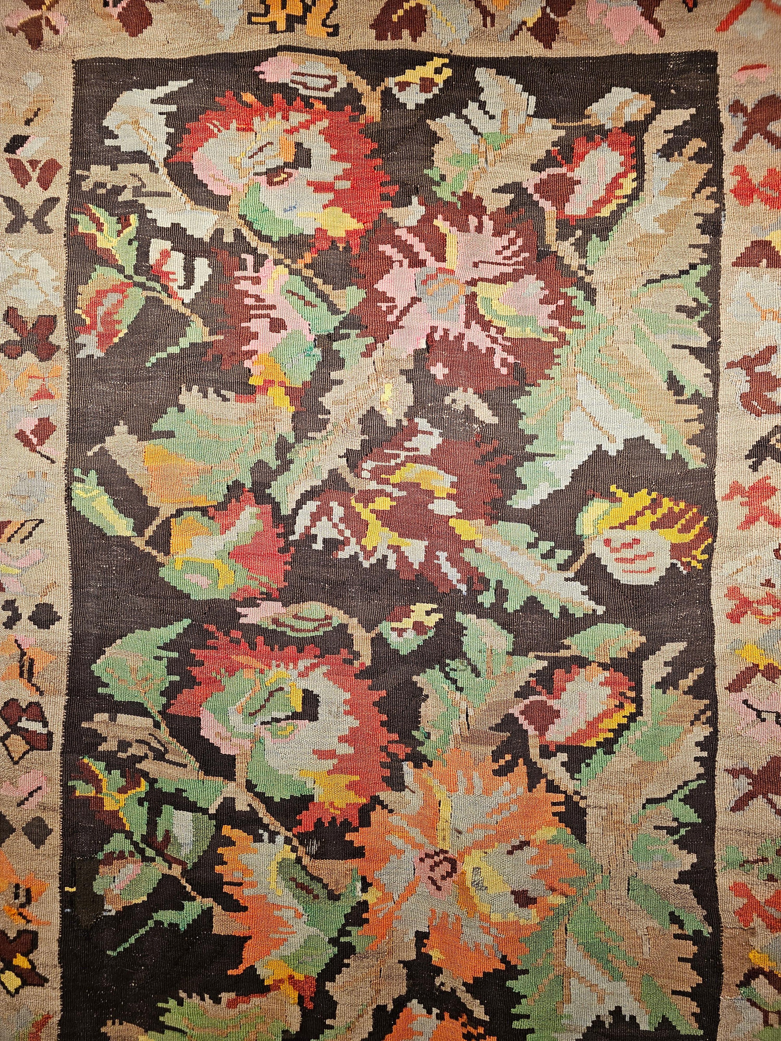 Vintage Karabagh Kilim runner with large floral designs and vibrant colors from the early 1900s. The kilim runner has bright and beautiful colors used in the three bouquets of flowers that cover the dark chocolate field. The floral design colors