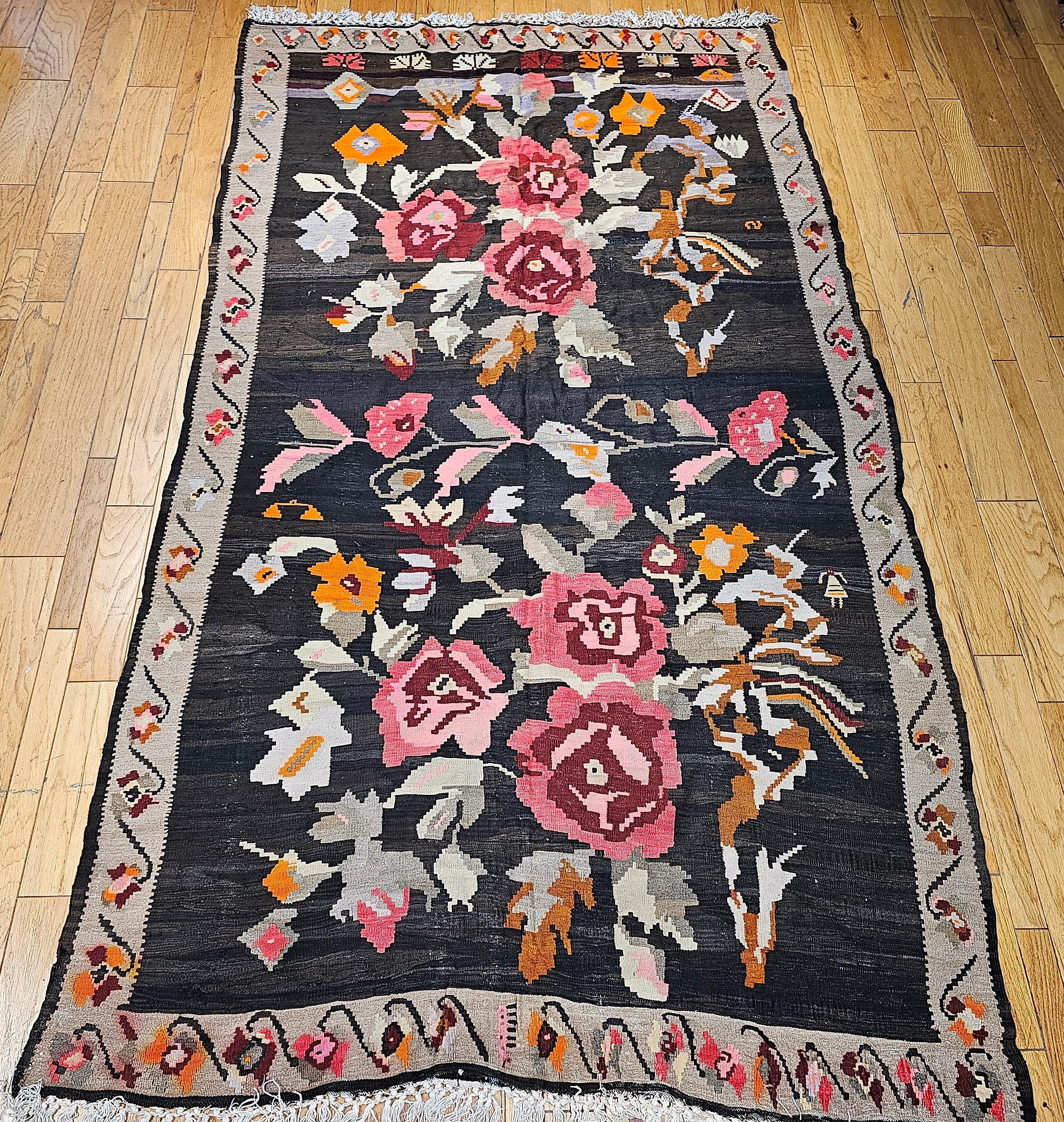 Vintage Karabagh Kilim gallery or room size rug with large floral design and vibrant colors from the early 1900s.   The kilim has bright and beautiful colors used in the two floral bouquets that cover the dark chocolate /brown field.  The floral