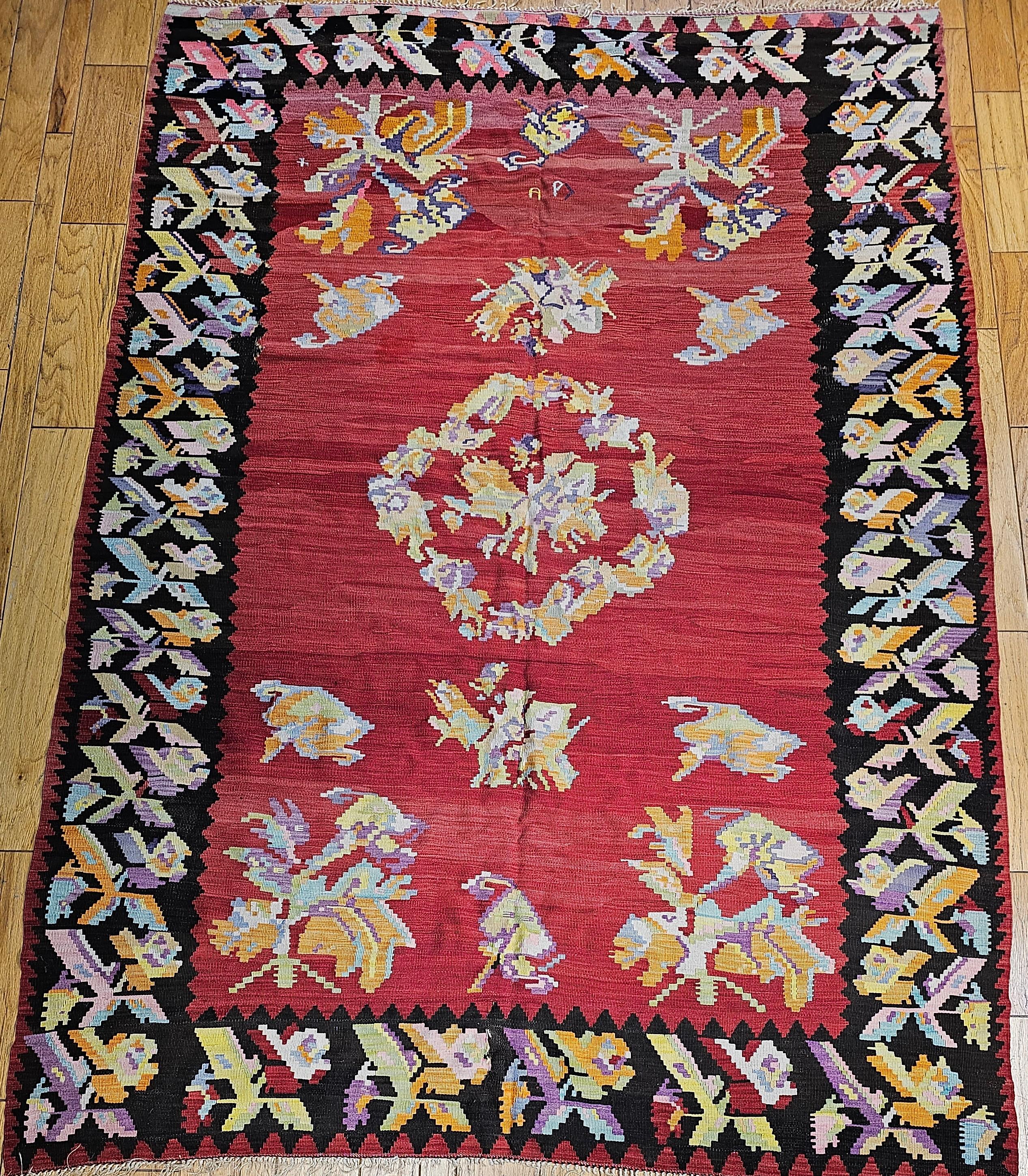  Vintage Karabagh Kilim room size rug with floral design and vibrant colors from the early 1900s.   The kilim has a bright and beautiful  floral pattern set in a brilliant red field.  The floral design colors include bright red, green, ivory, black,