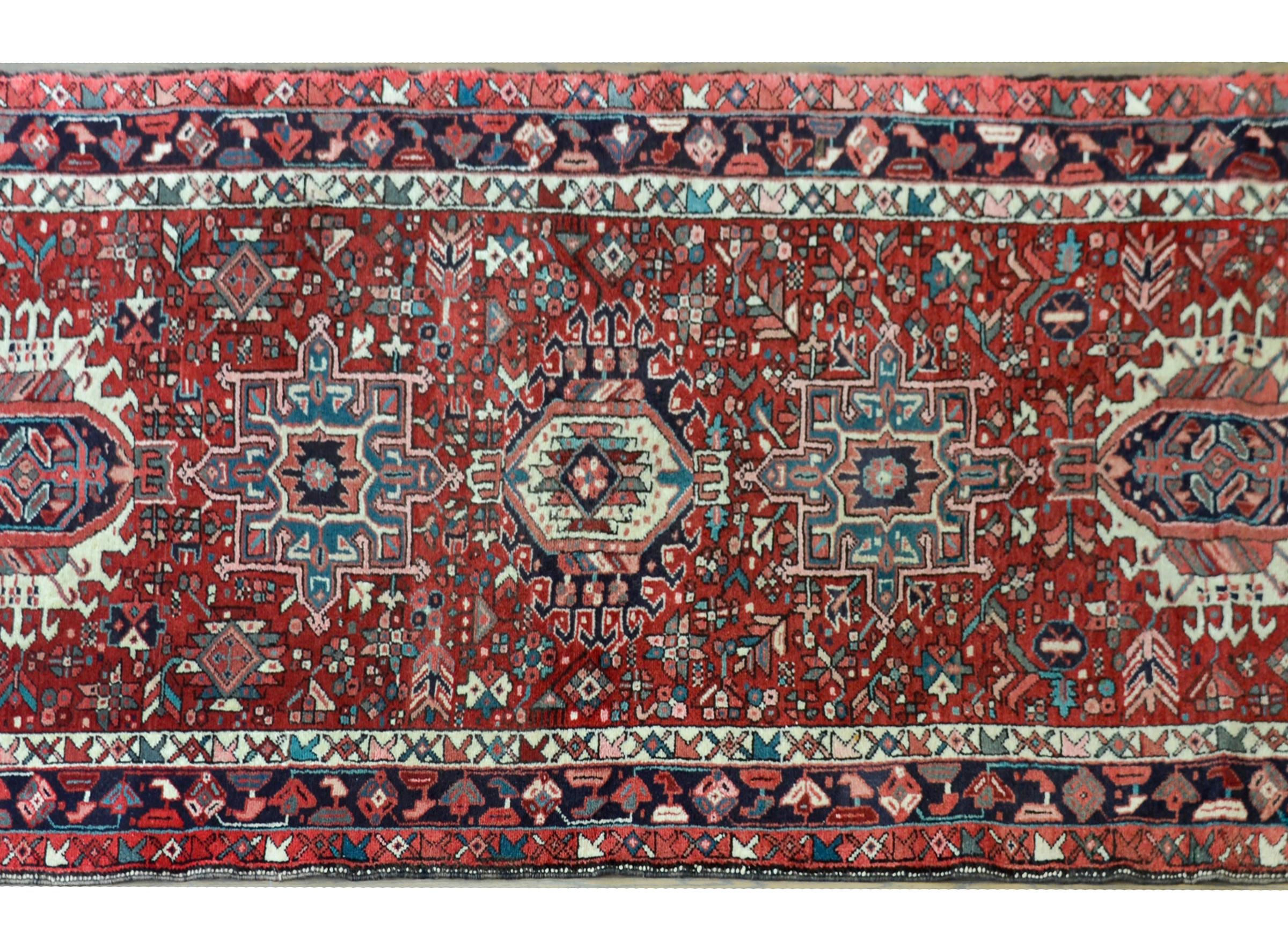 A wonderful vintage Persian Karadja runner with multiple large stylized floral medallions woven amidst a densely oven field of more flowers and scrolling vines, and surrounded a by a complemtary border.