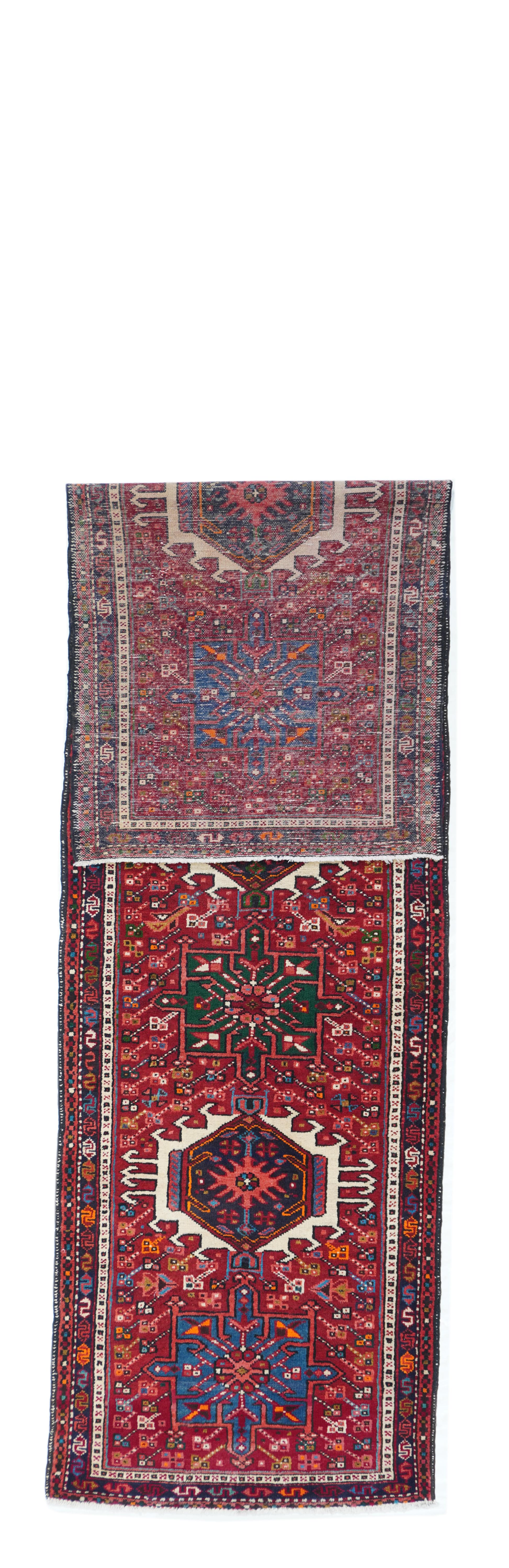 Vintage Karajeh Heriz Runner¬†2'8'' x 9'6''. This characteristic NW Persian rustic runner shows seven alternating octogramme and hooked hexagon medallions in abrashed light blue, medium blue, dark green and ecru. Tomato red field with radiating
