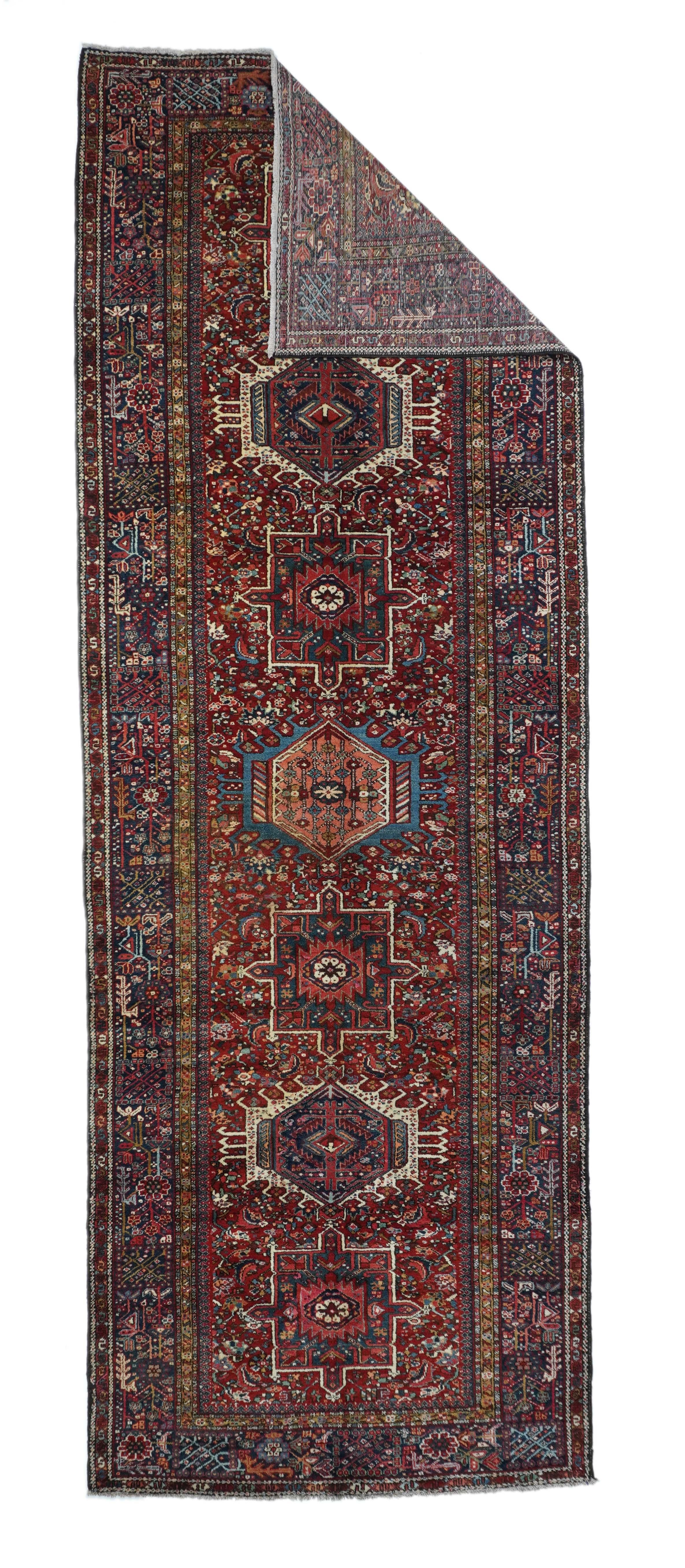 Vintage Karajeh Rug 4'8'' x 13'6''. Red field with seven alternating characteristic octogramme and hooked hexagon forms in ecru, light blue and navy. Small leaves and floral forms closely fill in the background. Navy border with herringboned leaves