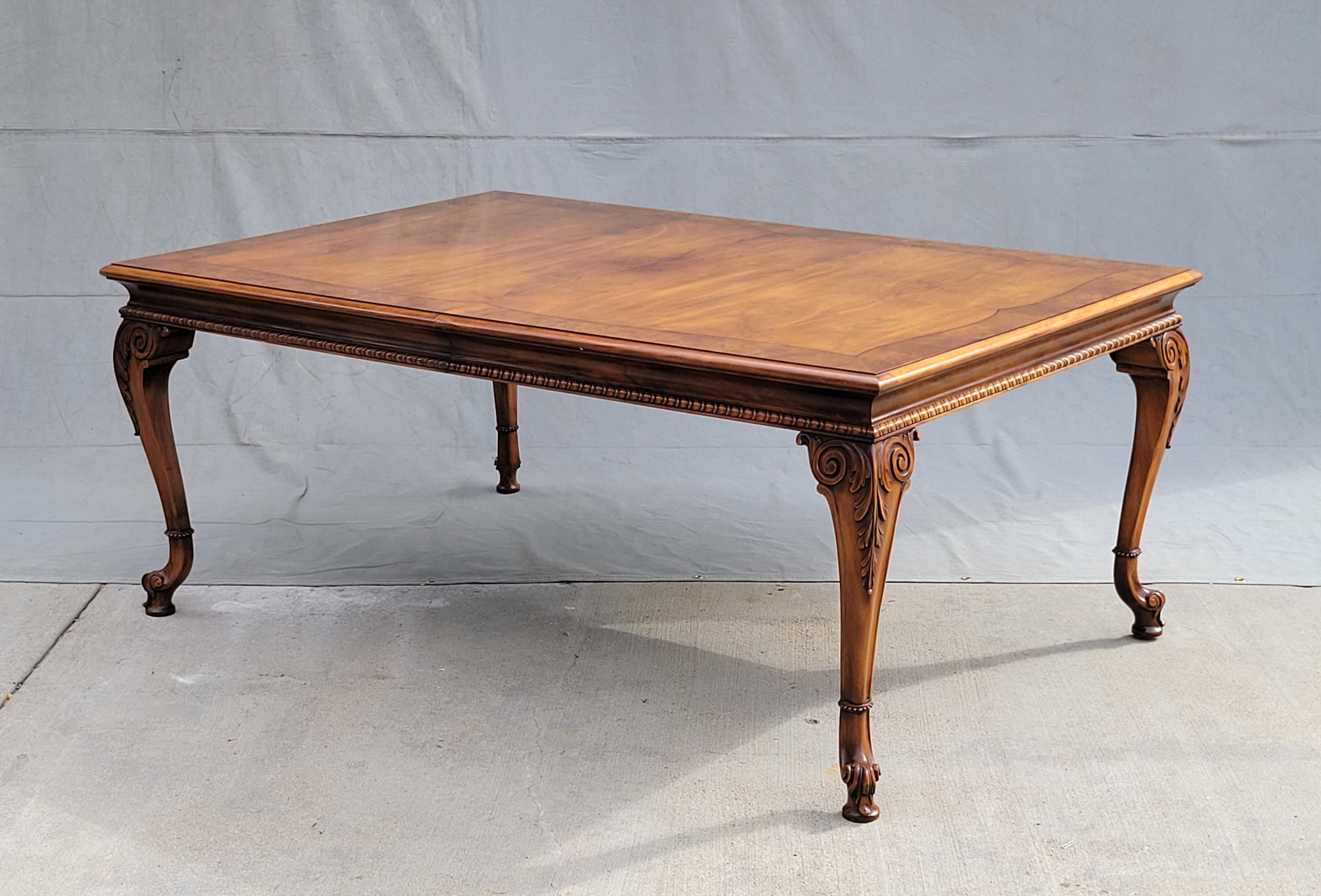 A gorgeous, classic vintage 1980s Karges burl walnut dining table with three leaves. Note the stunning carved cabriole legs on pad feet. A ring of beading surrounds each leg toward the bottom, giving a distinctive accent. A scalloped detail runs