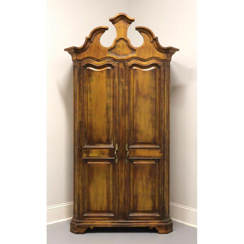 A French Transitional style armoire / linen press by Karges, of Evansville, Indiana, USA. Solid wood with distressed gold finish, metal hardware, ornately carved pediment top and bracket feet. Features two solid double panel doors revealing a cream