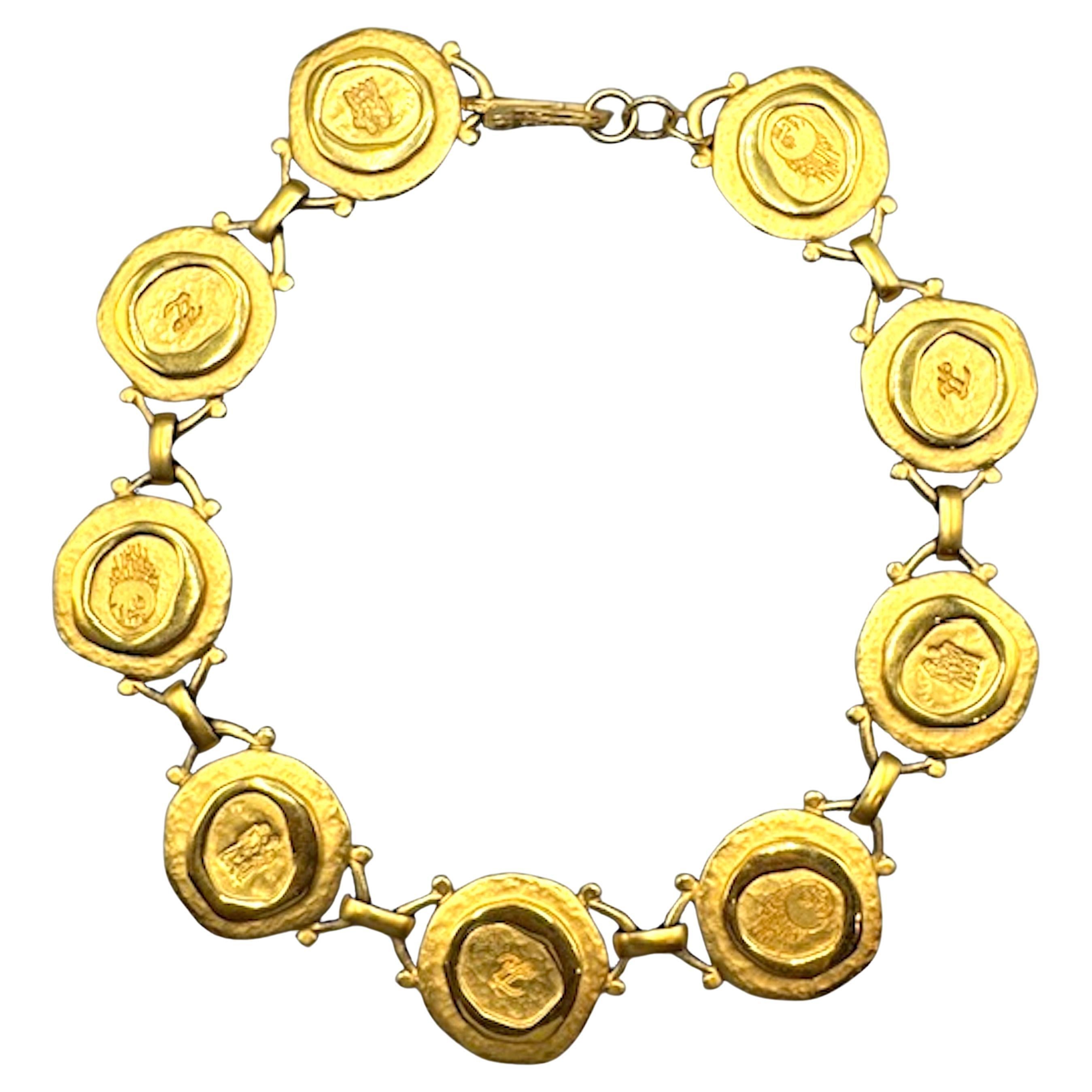 Diese auffällige Vintage-Halskette von Karl Lagerfeld zeichnet sich durch eine Reihe von runden Medaillons aus, die in einem fließenden, kragenartigen Design miteinander verbunden sind. Jedes Medaillon ist aus satiniertem, goldfarbenem Metall