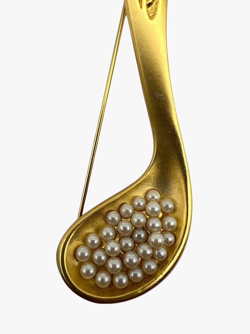 Vintage-Brosche von Karl Lagerfeld mit einem Löffel voller Kaviar aus Kunstperlen, 24 Karat vergoldet. 

Unterschrieben. KL-Monogramme. 

Jahr: 1992er

Zustand: ausgezeichnet. Keine sichtbaren Anzeichen von Verschleiß. 

Größe: 12