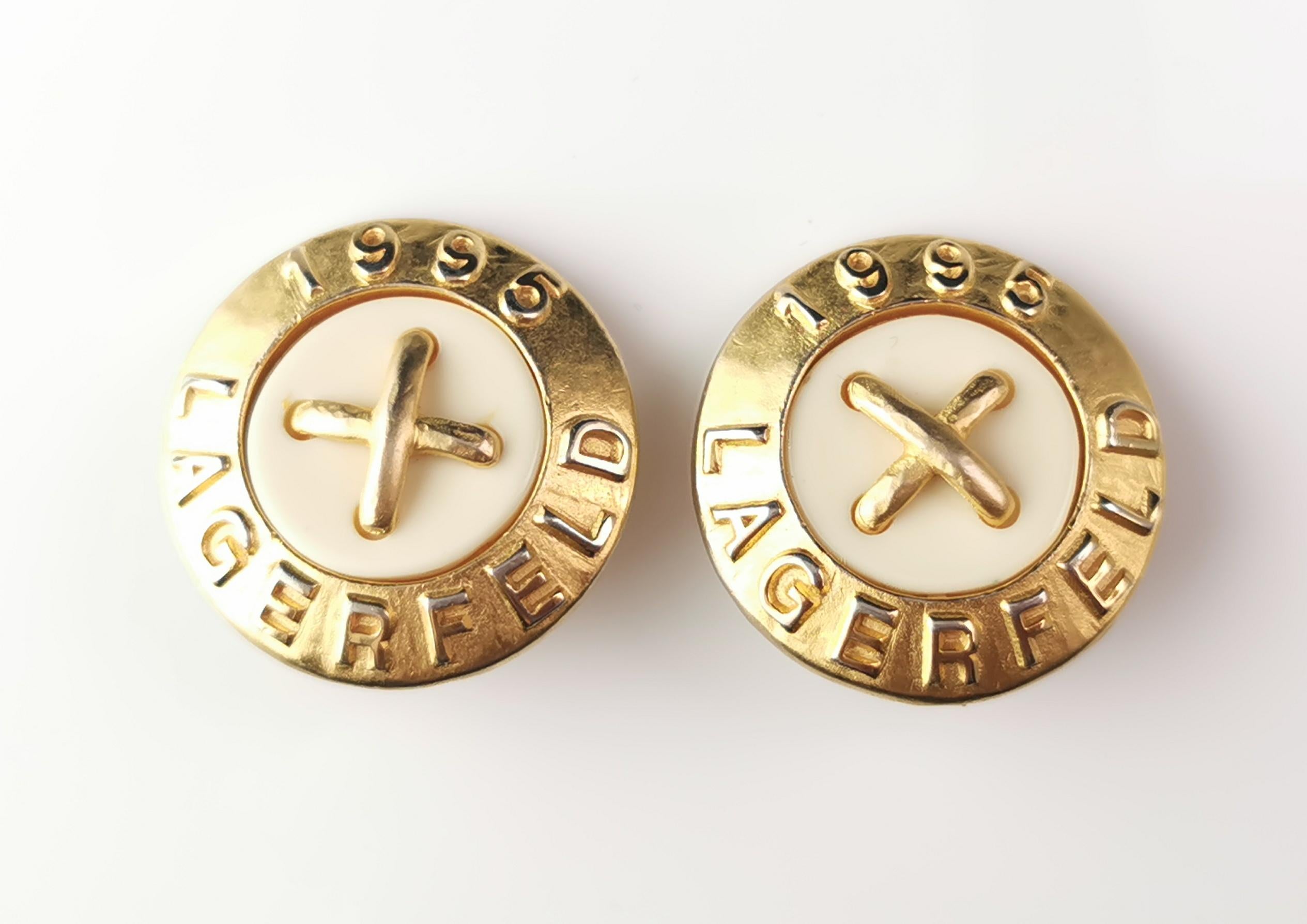 A rare pair of vintage Karl Lagerfeld 1995 clip on earrings.

These are large earrings in a matte gold tone metal with Karl Lagerfeld and 1995 in relief around the circular rim.

They feature a large cream circle to the centre with gold tone