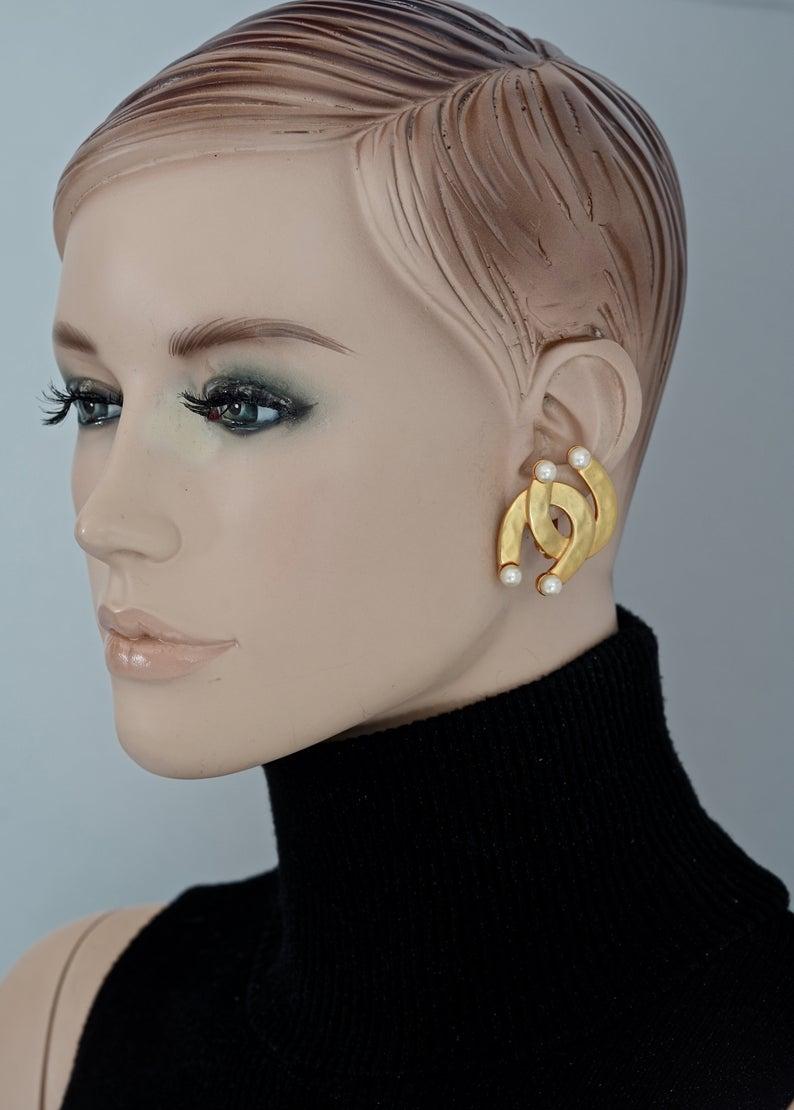 Vintage KARL LAGERFELD Double Horseshoe Pearl Earrings

Measurements:
Height: 1.61 inches (4.1 cm)
Width: 1.22 inches (3.1 cm)
Weight per Earring: 13 grams

Features:
- 100% Authentic KARL LAGERFELD.
- Interlocking horseshoe earrings.
- Accentuated