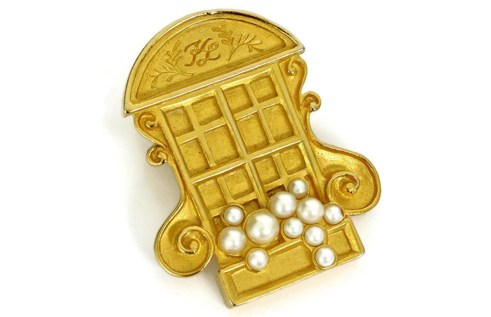 Vintage KARL LAGERFELD French Window Brooch

Measurements:
Height: 1 3/4 inches
Width: 1 3/8 inches


Features:
- 100% Authentic KARL LAGERFELD.
- Detailed French window embellished with Faux Pearls.
- Matte gold hardware.
- KL inscription on the