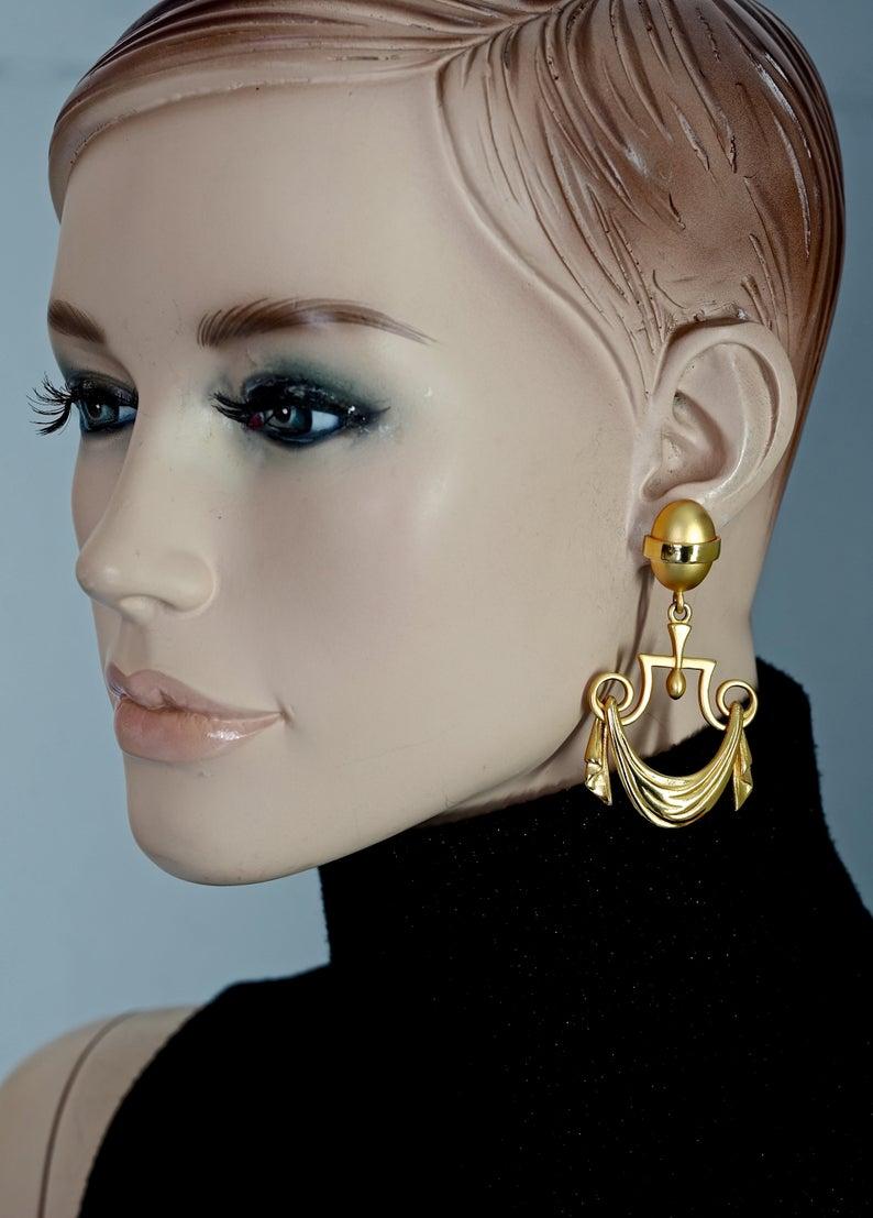 Vintage KARL LAGERFELD Greek Draped Curtain Dangling Earrings

Measurements:
Height: 2.67 inches (6.8 cm)
Width: 1.53 inches (3.9 cm)
Weight per Earring: 15 grams

Features:
- 100% Authentic KARL LAGERFELD.
- Greek draped curtain motif earrings.
-
