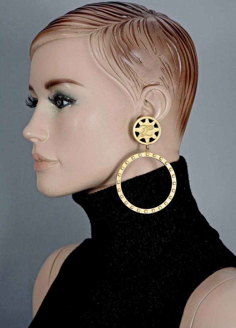 Vintage KARL LAGERFELD KL Logo Hoop Earrings

Measurements:
Height: 3.94 inches (10 cm)
Width: 2.36 inches (6 cm)
Weight per Earring: 37 grams


Features:
- 100% Authentic KARL LAGERFELD.
- Massive hoop earrings with KL logo.
- Brushed gold tone.
-