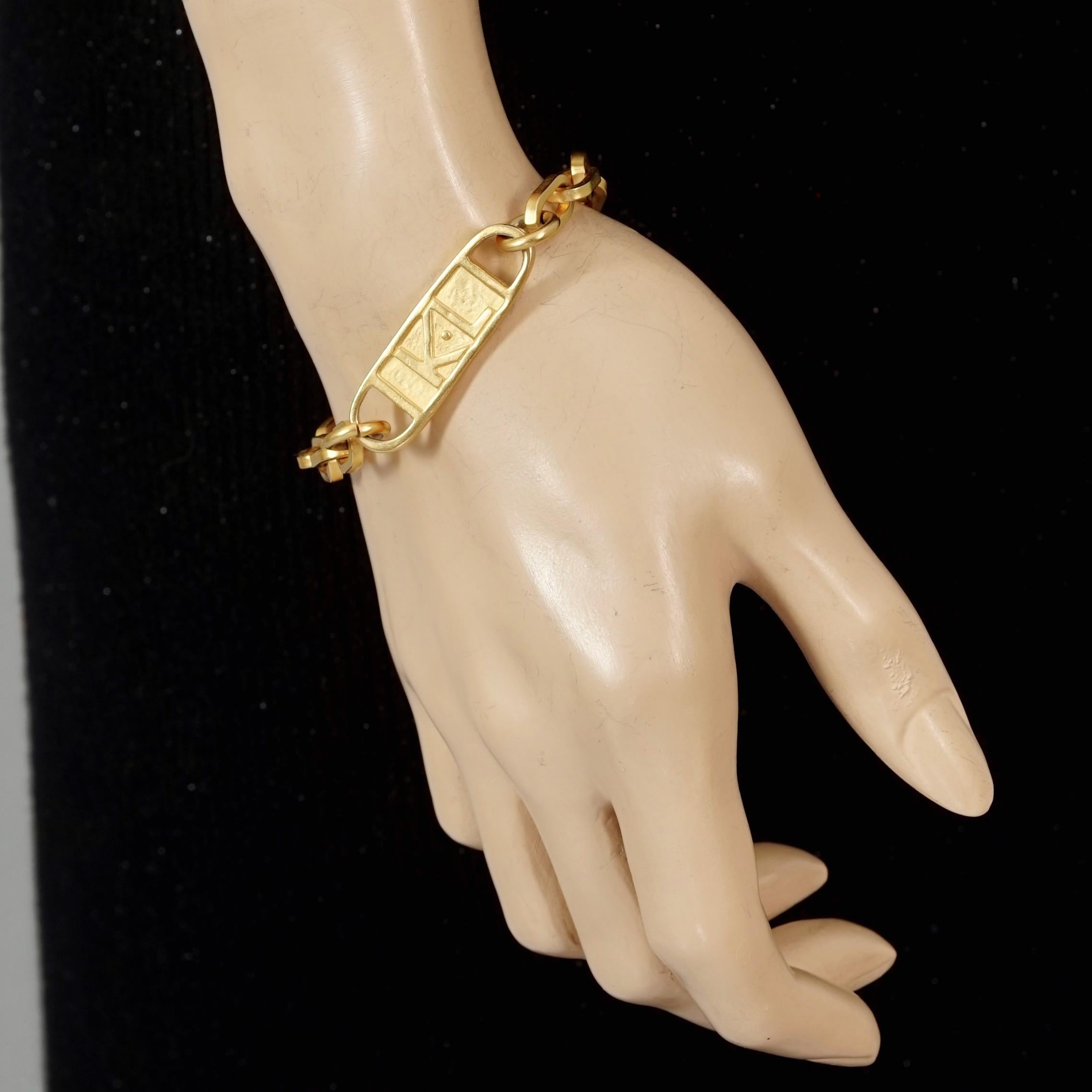 Vintage KARL LAGERFELD Logo ID Plate Chain Bracelet

Measurements:
Height: 0.47 inch (1.2 cm)
Wearable Length: 7.67 inches (19.5cm)

Features:
- 100% Authentic KARL LAGERFELD.
- Embossed KL logo on ID plate chain bracelet.
- Gold tone hardware.
-