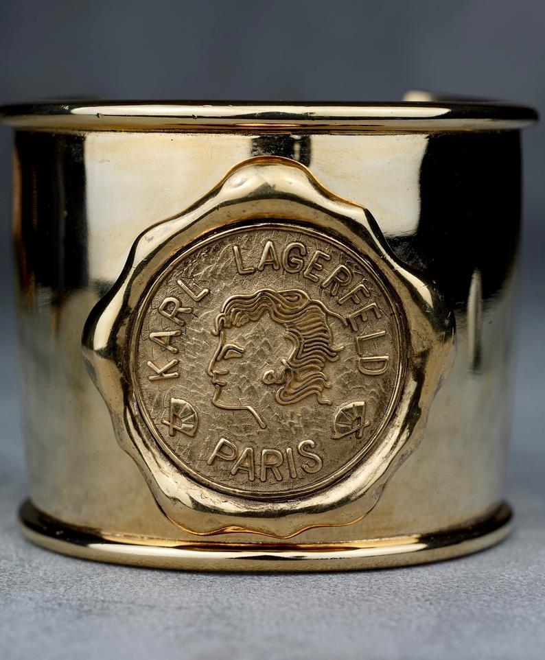 Vintage KARL LAGERFELD Logo Wax Seal Coin Medallion Cuff Bracelet

Measurements:
Height: 2.36 inches (6 cm)
Inner Circumference: 7.28 inches (18.5 cm)

Features: 
- 100% Authentic KARL LAGERFELD.
- Wax seal motif with embossed KARL LAGERFELD PARIS