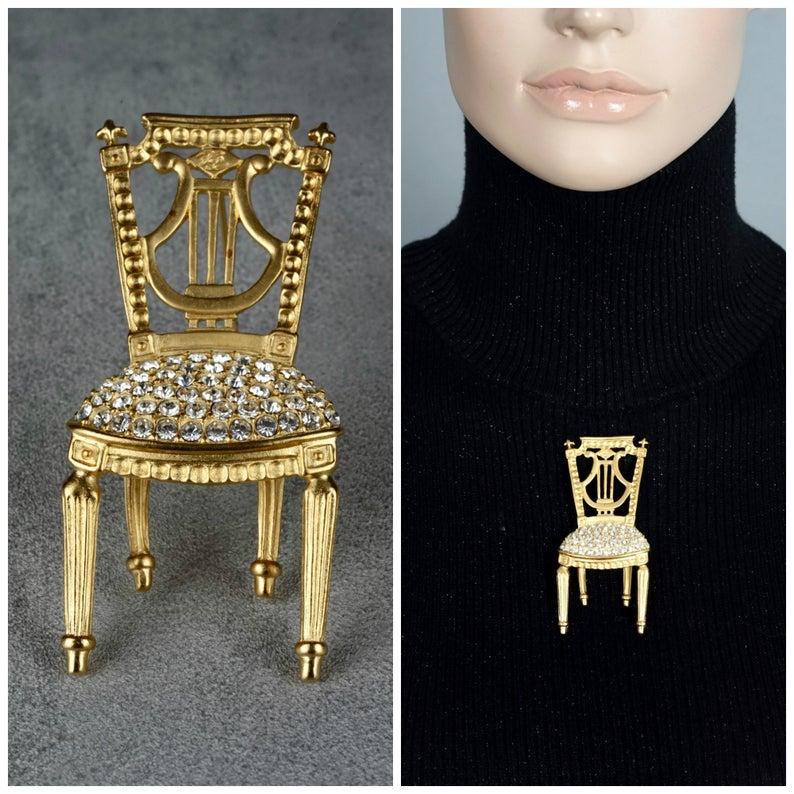 Vintage KARL LAGERFELD Lyre French Chair Rhinestone Brooch

Measurements:
Height: 3.15 inches (8 cm)
Width: 1.45 inches (3.7 cm)
Depth: 0.59 inch (1.5 cm)

Features:
- 100% Authentic KARL LAGERFELD.
- French chair with lyre back rest.
- Studded with