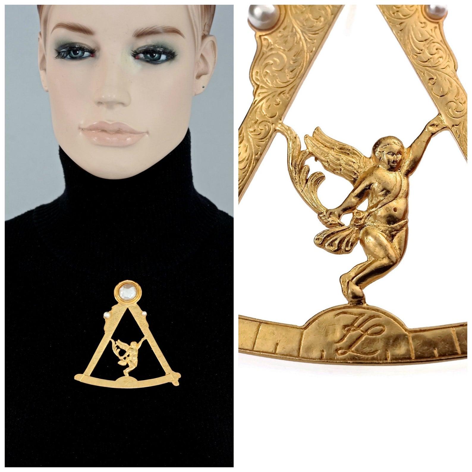 Vintage KARL LAGERFELD Scale Angel Cherub Pearl Logo Novelty Brooch

Measurements:
Height: 3.77 inches (9.6 cm)
Width: 3.38 inches (8.6 cm)

FEATURES:
- 100% Authentic KARL LAGERFELD.
- Novelty scale with an angel/ cherub at the centre.
-