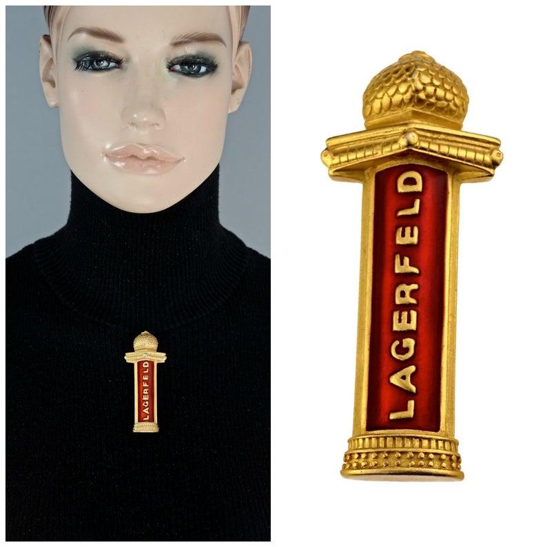 Vintage KARL LAGERFELD Spelled Enamel Tower Brooch

Measurements:
Height: 2.95 inches (7.5 cm)
Width: 1.18 inches (3 cm)

FEATURES:
- 100% Authentic KARL LAGERFELD.
- Novelty tower brooch with spelled LAGERFELD on red enamel.
- Gold tone.
- Good