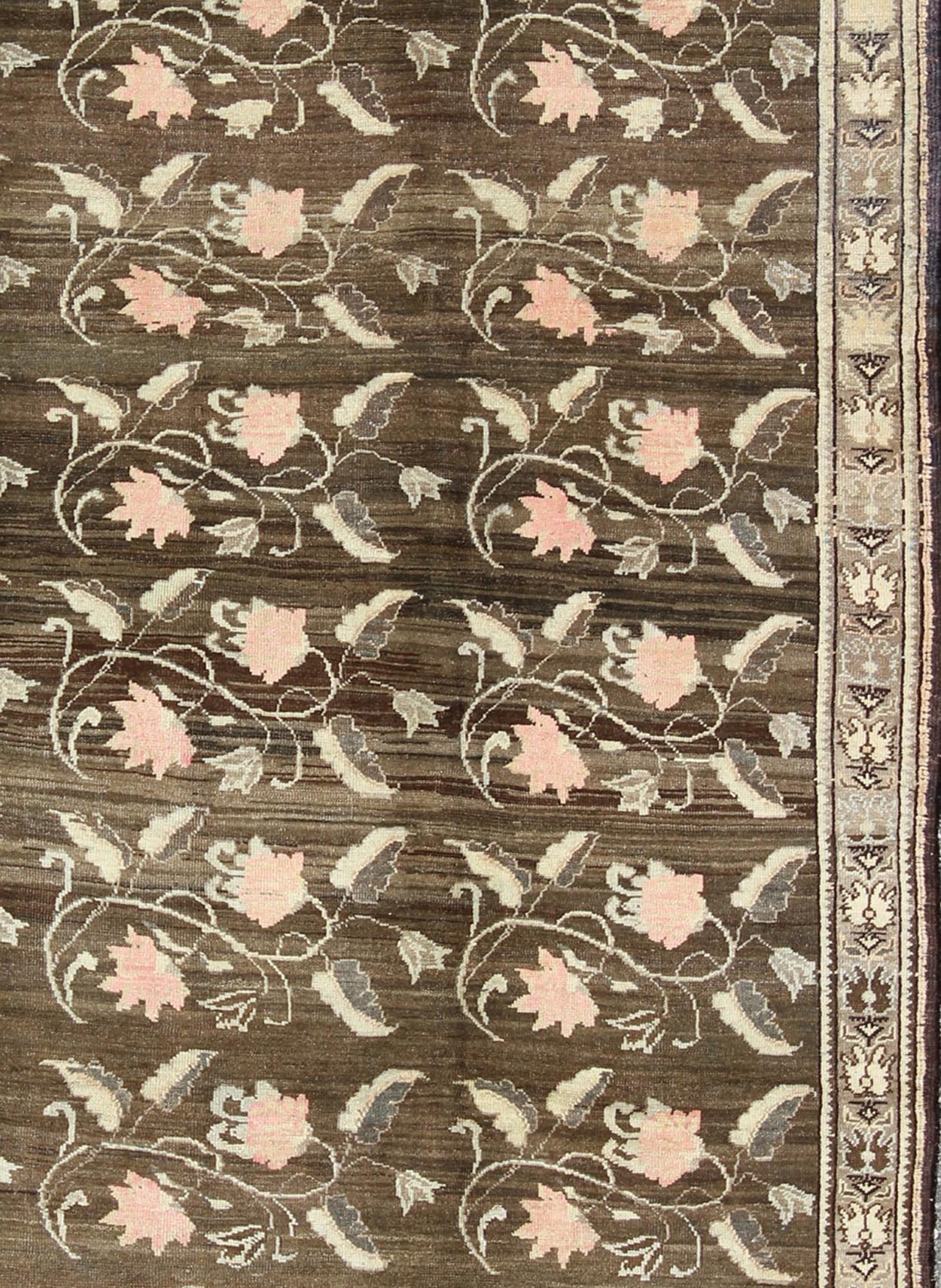 Measures: 7'5 x 11'4

Set on a dark greenish-brown background, the all-encompassing floral pattern of this vintage Turkish Kars is unique. The pale pink and peach-colored roses featured in this unique piece are accompanied by light green leaves