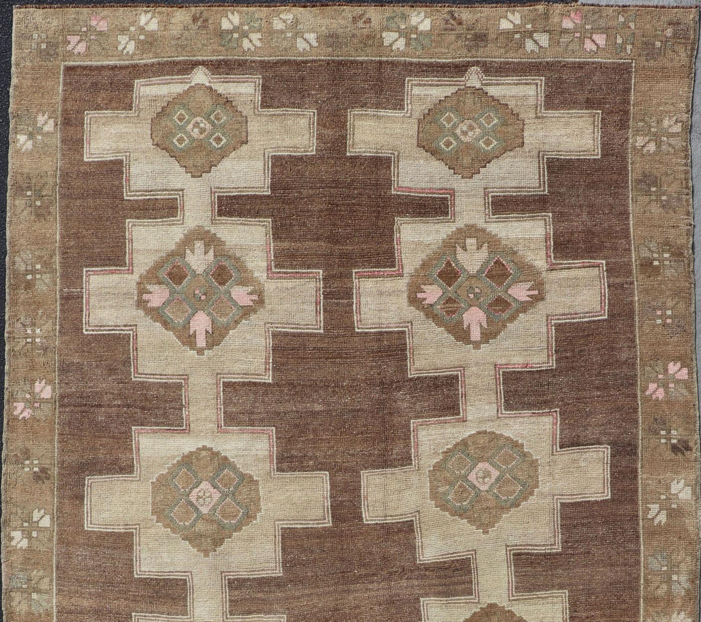 Stacked in two rows of geometric medallions, this Vintage Turkish Kars wide gallery runner displays great geometry in chocolate Brown background with Colors such as Tan, Taupe and Light Green. Keivan Woven Arts rug / EN-179569 type / Turkish Kars