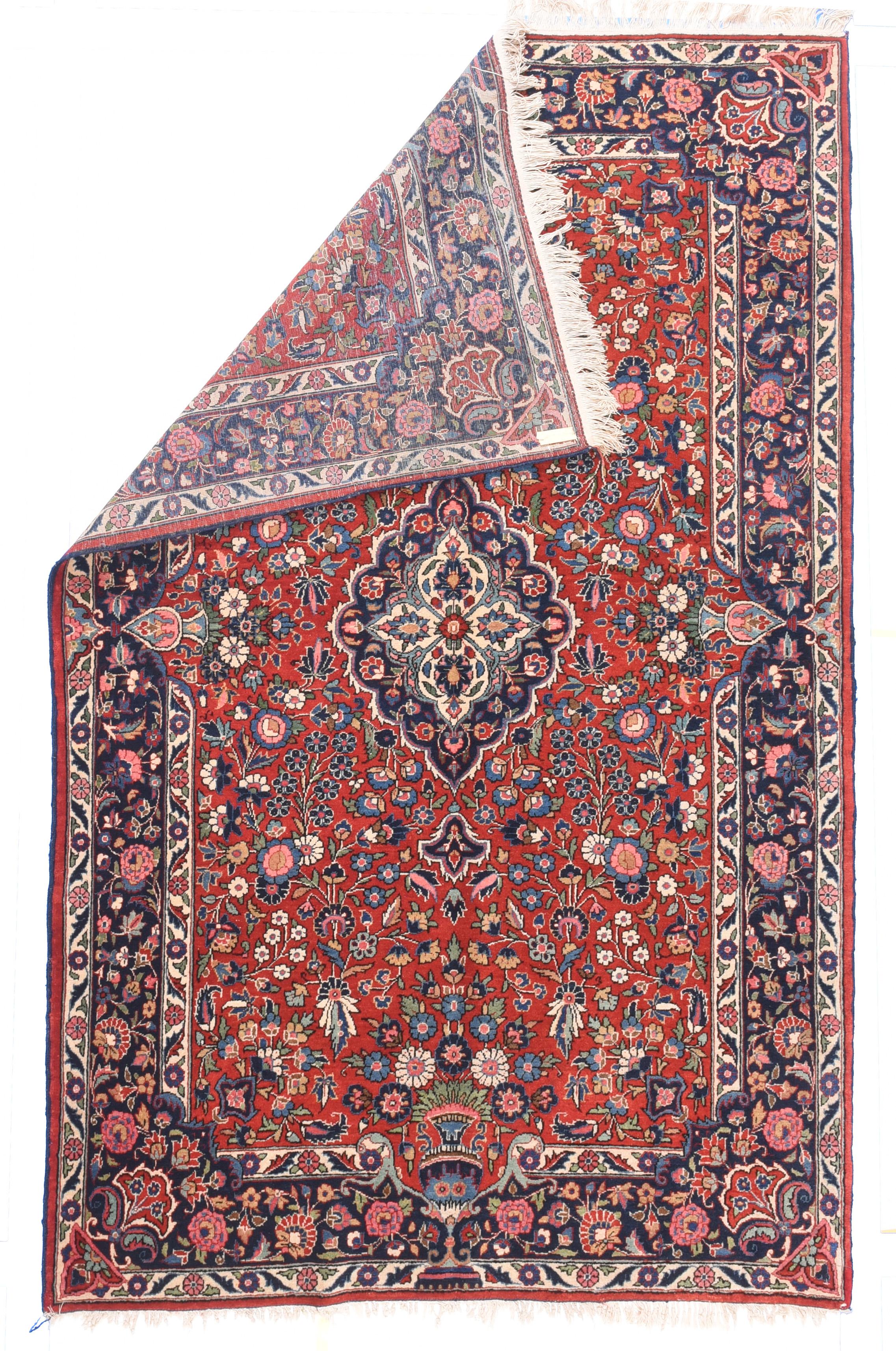 Vintage Kashan Rug 4'4'' x 6'10''. The crisp red field, with a wide variety of Persian garden flowers, flows around the small lightly scalloped navy medallion with reduced pendants, and is invaded by vases and floral bouquets from the navy border on