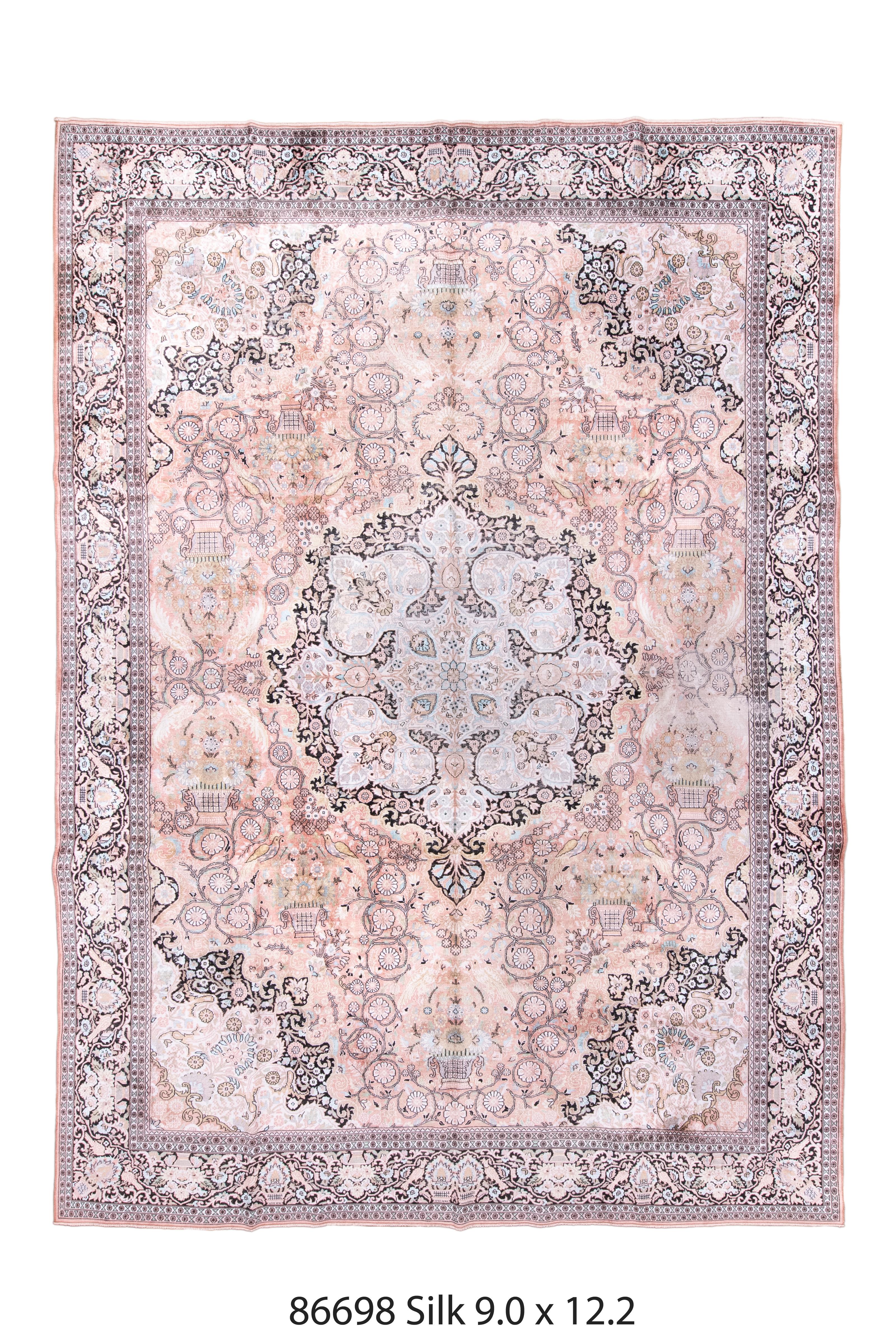 This well-woven urban silk carpet in the Tabriz manner, presents a cream and black round medallion with an inner pendanted octogramme. Large and small birds, vases, rosettes and coiling vines fill the light field. Black and cream corners. Black